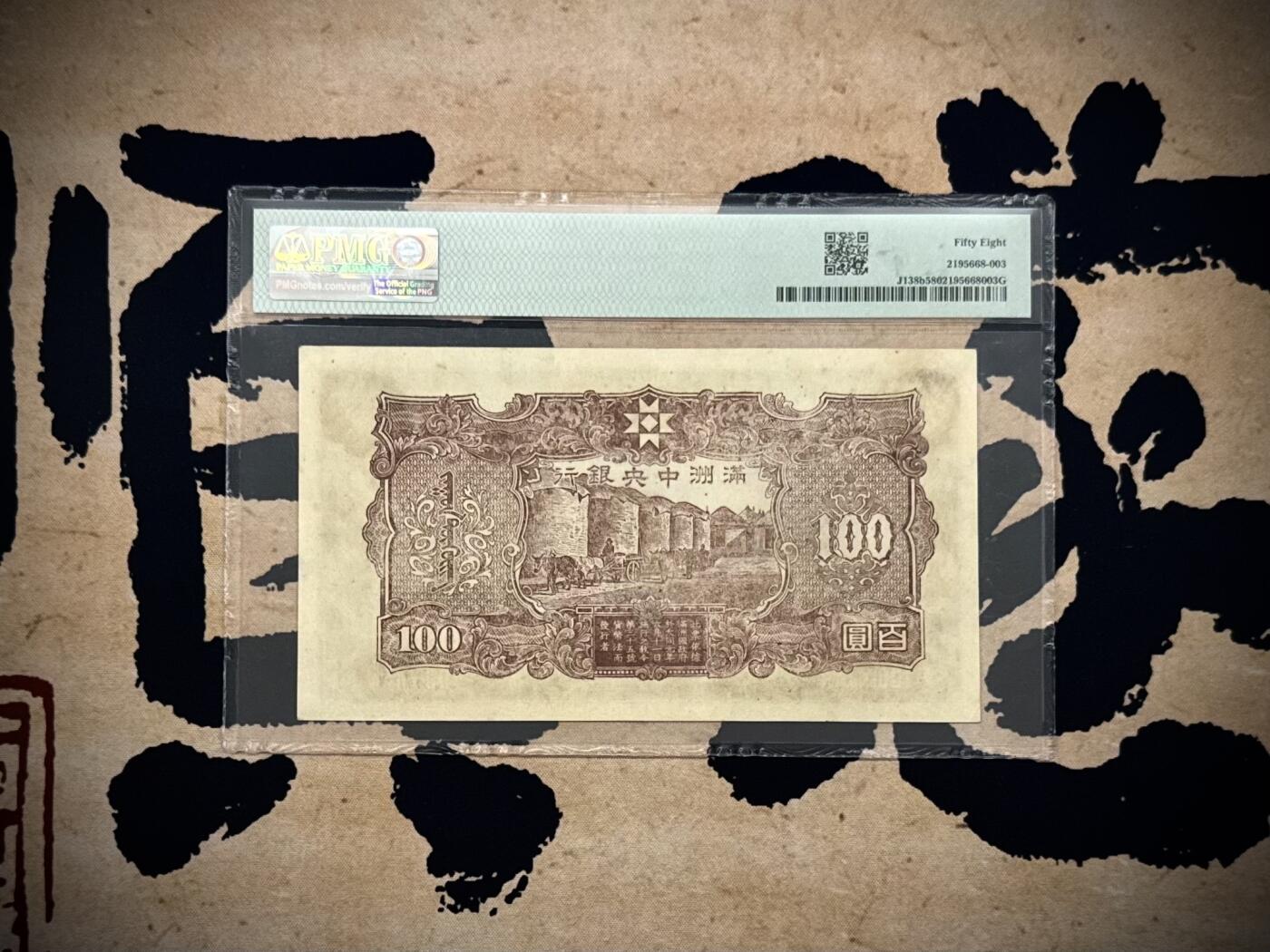 【乾奕收藏】出民国33年1944年满洲中央银行百圆，正面孔子大殿，背面粮仓图案，美国PMG58分，号码全程无47，民国纸币经过80年能保存如此品相实属难得，喜欢的老板不要错过，评级币一切以分数为准，售出非假不退 