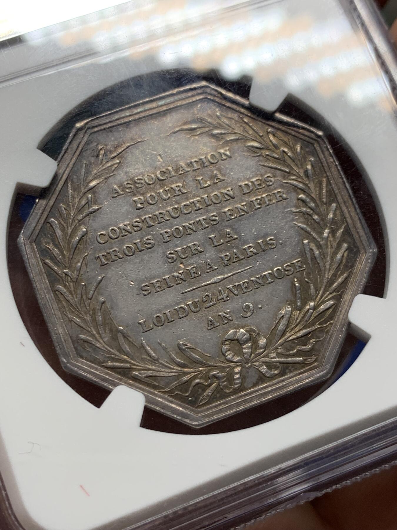 《竞宝斋》第408场 周日，周一，2场连拍 （全场包邮） NGC AU58 法国塞纳河三铁桥建设协会银章 油灯边铭（1832-1841），欧洲五彩老包浆状态，塞纳河畔的早晨，金色的阳光洒在波光粼粼的河面上，沿岸的建筑都沐浴在晨光下，一片宁静的景象