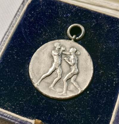 甄臻铺-世界币章拍卖（第28期），送拍享返佣金等优惠多多 1928年英国拳击比赛奖牌，正面是两个拳击手对战图案，背面是百合花图案和LXIII罗马数字。重20.4g，直径32mm。带原盒