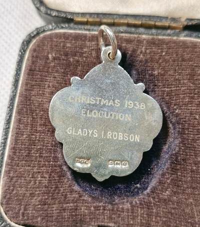 甄臻铺-世界币章拍卖（第28期），送拍享返佣金等优惠多多 The Incorporated London Academy of Music 1938年圣诞节演讲银奖章，正面是学院徽章图案，背面刻有CHRISTMAS 1938 ELOCUTION GLADYS I. ROBSON字样，品相如图，珐琅彩边缘完整，背面刻字清晰重13.6g，长27mm。带原盒