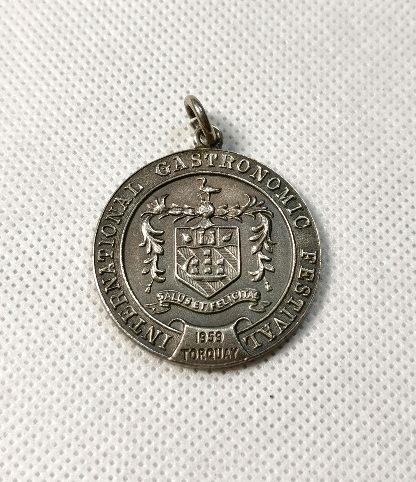 甄臻铺-世界币章拍卖（第28期），送拍享返佣金等优惠多多 1959年英国Torquay国际美食节纪念银章，双面浮雕工艺，正面是盾形纹章，背面是烹饪工具图案，重15.6g，直径33mm