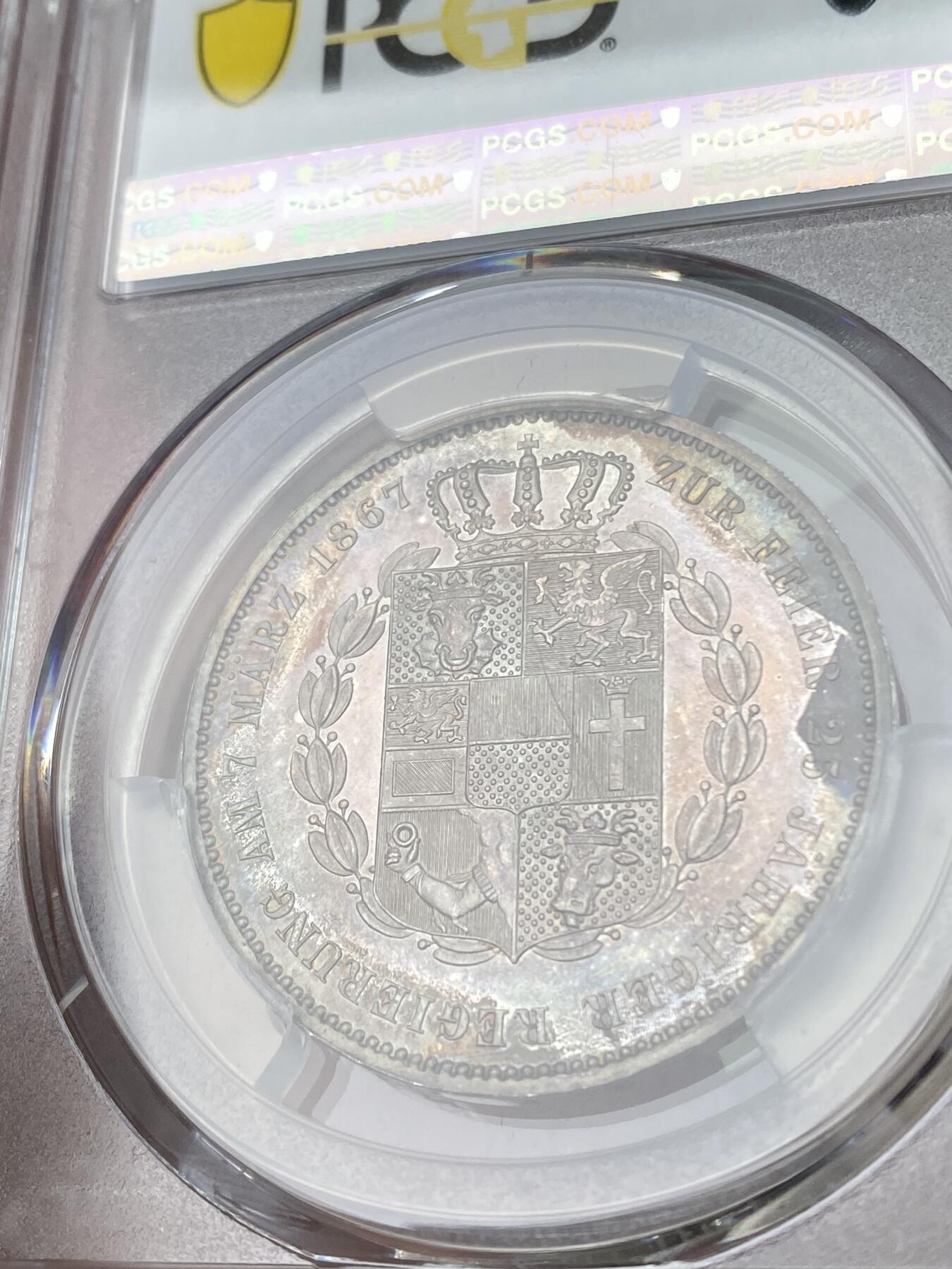 万国钱币拍卖第051期 PCGS MS64 1867年德国梅克伦堡-什未林盾徽1泰勒 盾徽华丽异常的小邦泰勒 卷藏式的七彩包浆环绕 镜面感很强 顶级收藏品质