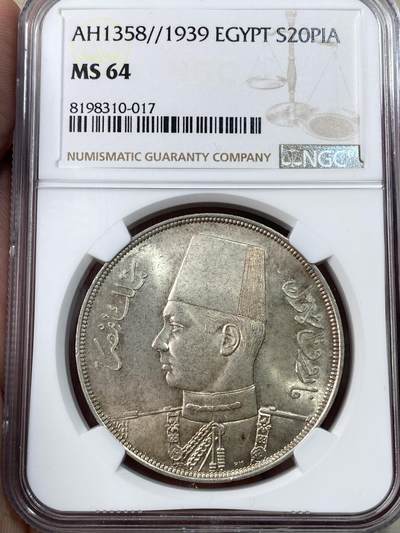 万国钱币拍卖第051期 - NGC MS64 埃及1939年法鲁克国王20皮阿斯特大银币 正面刻有埃及国王，同时也是著名钱币收藏家的法鲁克头像，背面阿拉伯文和花卉装饰，原味淡彩，车轮转光，NGC更高分仅2枚。