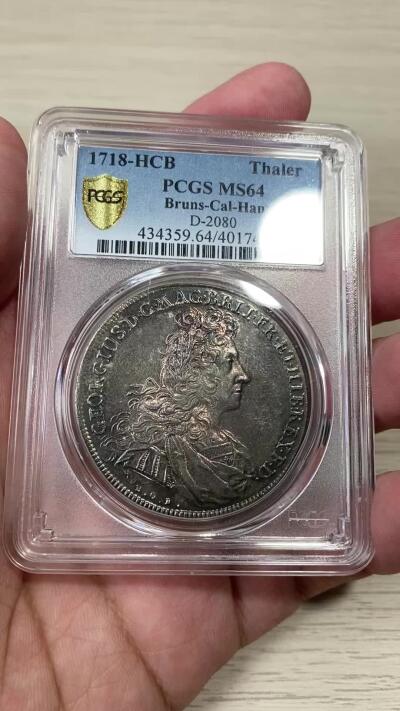 万国钱币拍卖第051期 NGC MS64 1718布伦瑞克-吕纳堡-汉诺威狮马盾徽大泰勒 极其罕见的一枚英系泰勒 正面君主为汉诺威选帝侯同时也是英国汉诺威王朝的第一位国王乔治一世 而这位英语不太流利的国王只能任命大臣替他处理政务 由此也成为了英国首相一职的开端 经典汉诺威狮马纹章 极其绚丽的欧陆五彩 一枚英德双修的顶级藏品 PC唯一冠军分