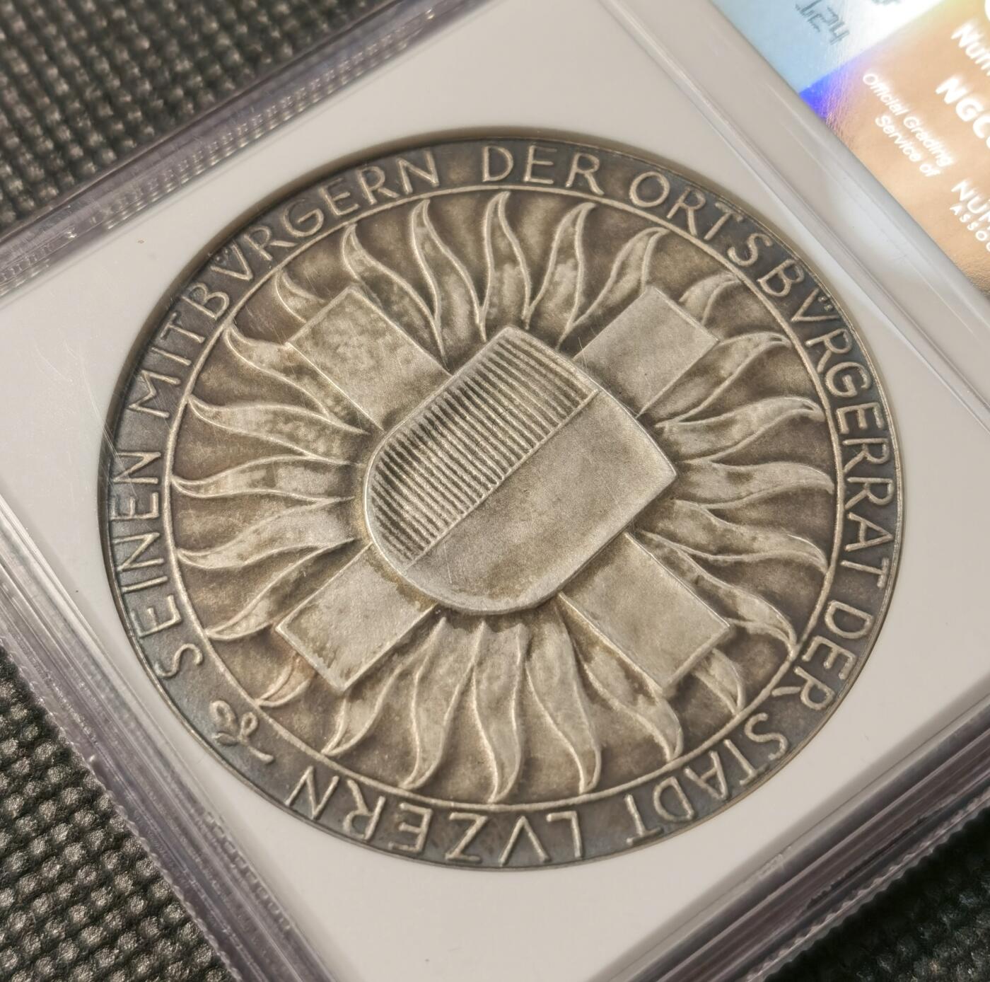 甄臻铺-世界币章拍卖（第30期），送拍享返佣金等优惠多多 NGC-MS64 瑞士1918年忠诚边防军颁发的纪念银章，直径45毫米，参考手册编号AEPPLI-279。正面是士兵持枪侧脸像，背面是盾牌和火焰纹章图案，由当地市政厅授权发行，工艺精湛