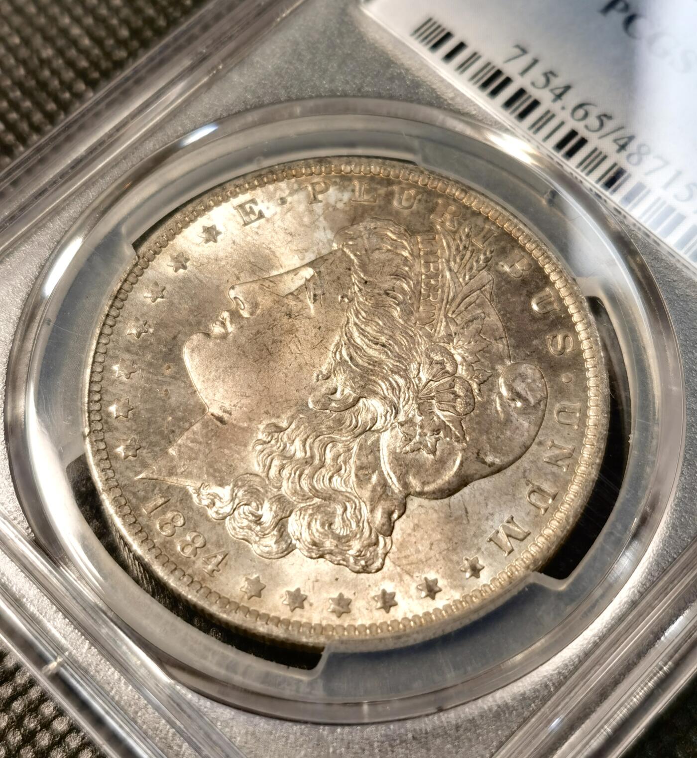 甄臻铺-世界币章拍卖（第30期），送拍享返佣金等优惠多多 PCGS-MS65 1884年O版摩根，正面紫金色包浆，状态极佳，阴阳脸卷首