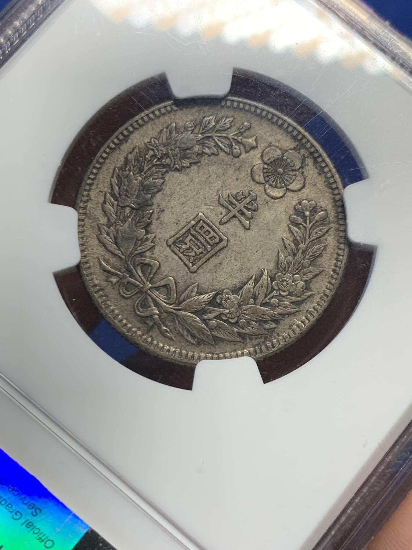 《竞宝斋》第415场 周日，周一，2场连拍 （全场包邮） NGC AU53  朝鲜1907年光武十一年半圆 小版稀少年份 黑金自然老彩，正面蟠龙戏珠图，龙身盘踞如环，背面上方为“李花章”（五瓣木槿花），下方交叉的桔梗花（左）与李花（右），低评状态，舒服怡人
