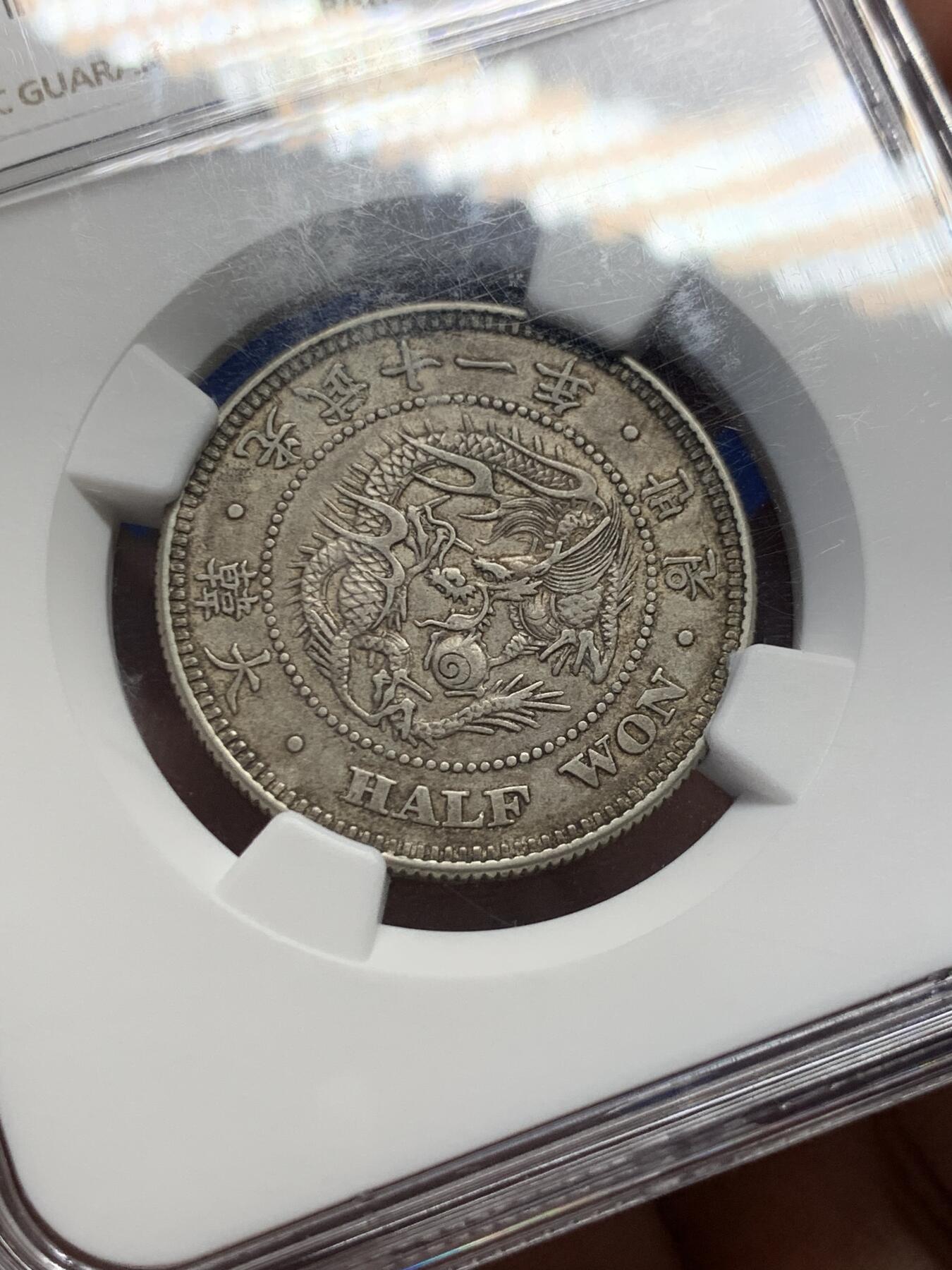 《竞宝斋》第417场 周日，周一，2场连拍 （全场包邮） NGC AU58  朝鲜1907年光武十一年半圆 小版稀少年份 百年原味通体自然老彩，正面蟠龙戏珠图，龙身盘踞如环，背面上方为“李花章”（五瓣木槿花），下方交叉的桔梗花（左）与李花（右），低评UNC状态 舒服怡人