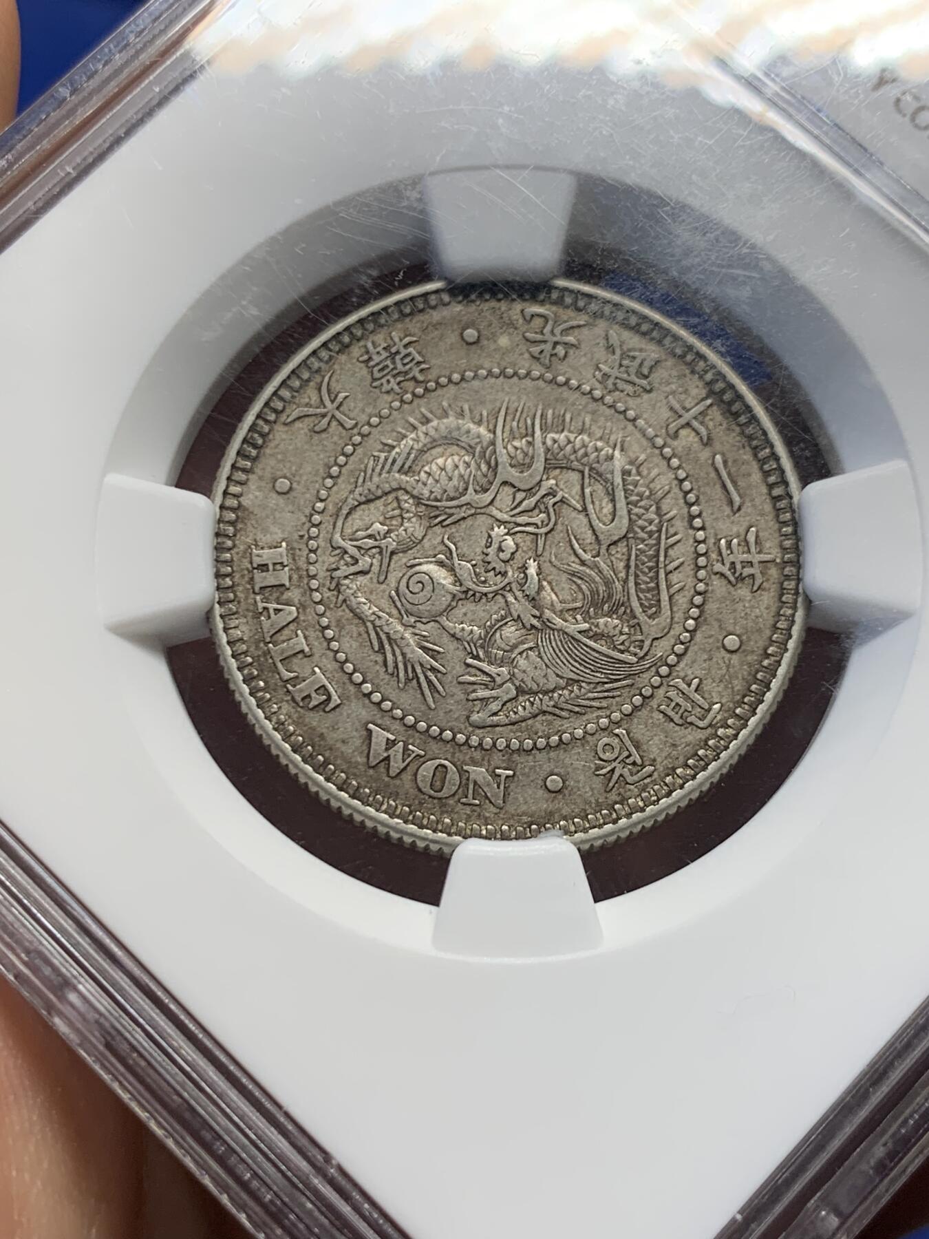 《竞宝斋》第417场 周日，周一，2场连拍 （全场包邮） NGC AU58  朝鲜1907年光武十一年半圆 小版稀少年份 百年原味通体自然老彩，正面蟠龙戏珠图，龙身盘踞如环，背面上方为“李花章”（五瓣木槿花），下方交叉的桔梗花（左）与李花（右），低评UNC状态 舒服怡人