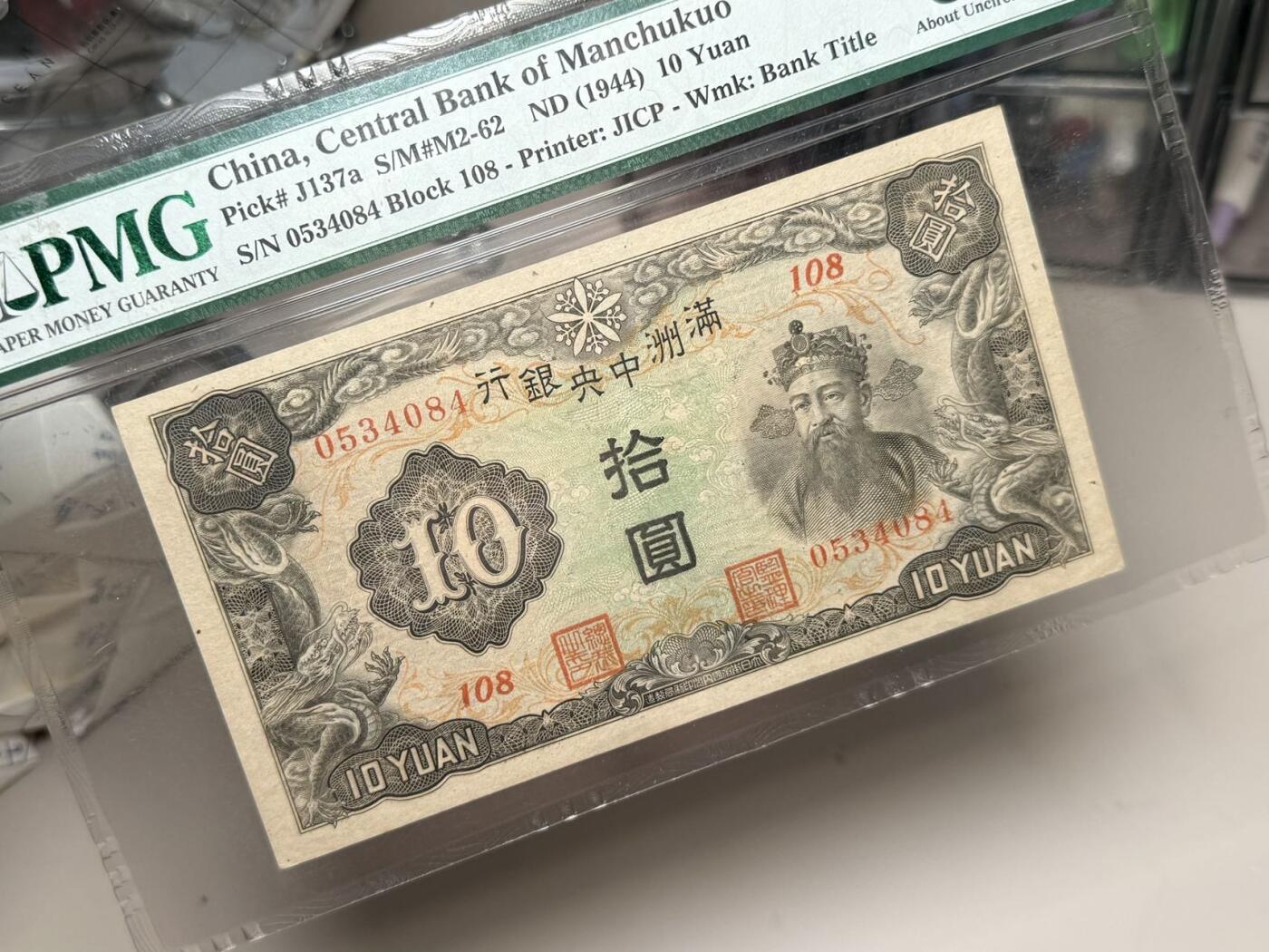 （自动截拍）PMG评级民国纸币专拍第20250911期，全场包邮 【乾奕收藏】出民国33年1944年满洲中央银行拾圆，财神赵公明图案，美国PMG55E