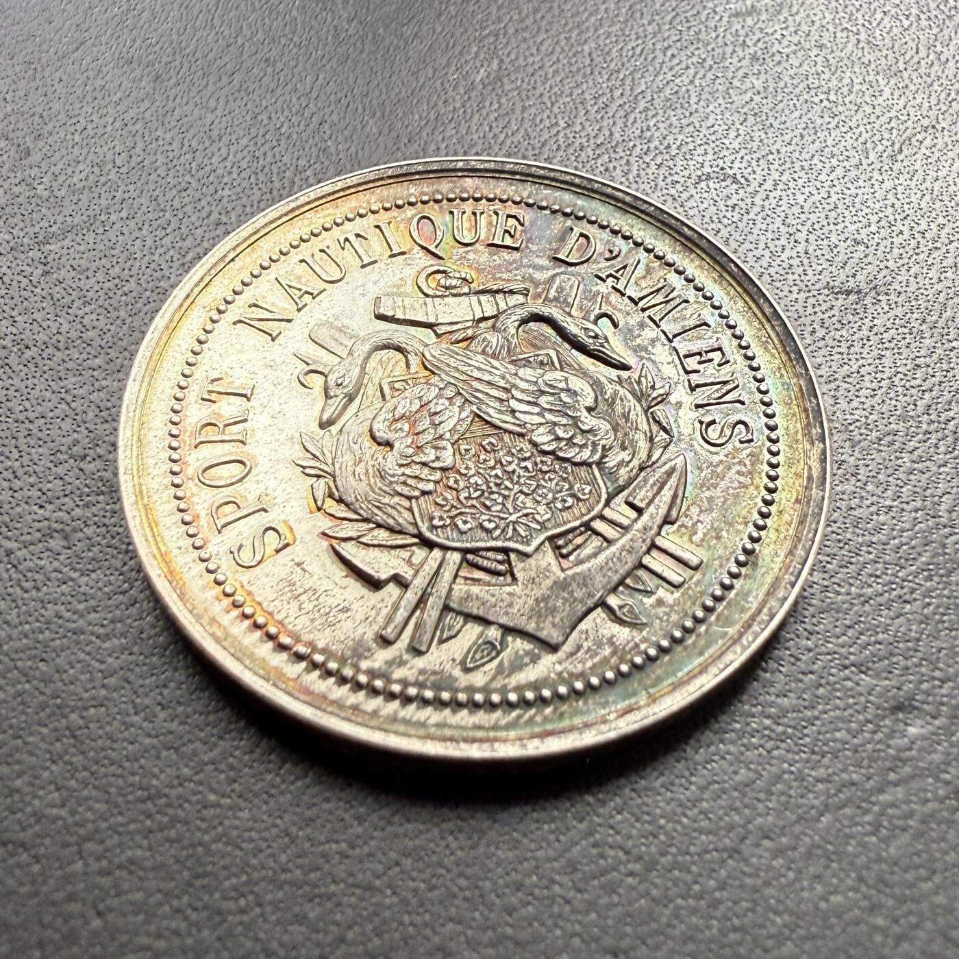 「木头集藏」章牌专场-第61场 法国昂热水上运动协会银章，直径：33 mm，16.2 g，边铭：丰饶角 ARGENT，正面刻画天鹅、船锚及船桨等元素，寓意水上运动的优雅、灵动，少见银章，品相不错，彩色氧化很美！
