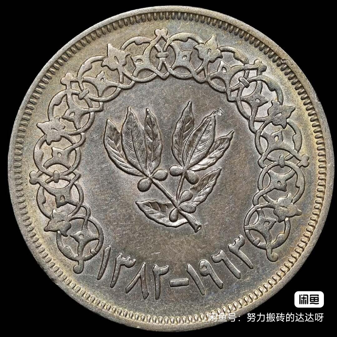 1963年阿拉伯也门共和国1里亚尔银币。银币重19.75g，含银量72%。正面上方为阿拉伯文“جمهوريّة العربية اليمنية”，意为“也门阿拉伯共和国”，中间是“1里亚尔”，并以圆圈环绕，下方有倒U形装饰。背面有一个带有八片叶子的树枝图案，底部左侧为阿拉伯纪年公元1963年，底部右侧为西历“1963”。市场上较为少见的品种。叶子图案很清晰流通好品带点底光，售出不退不换菜鸟包邮。