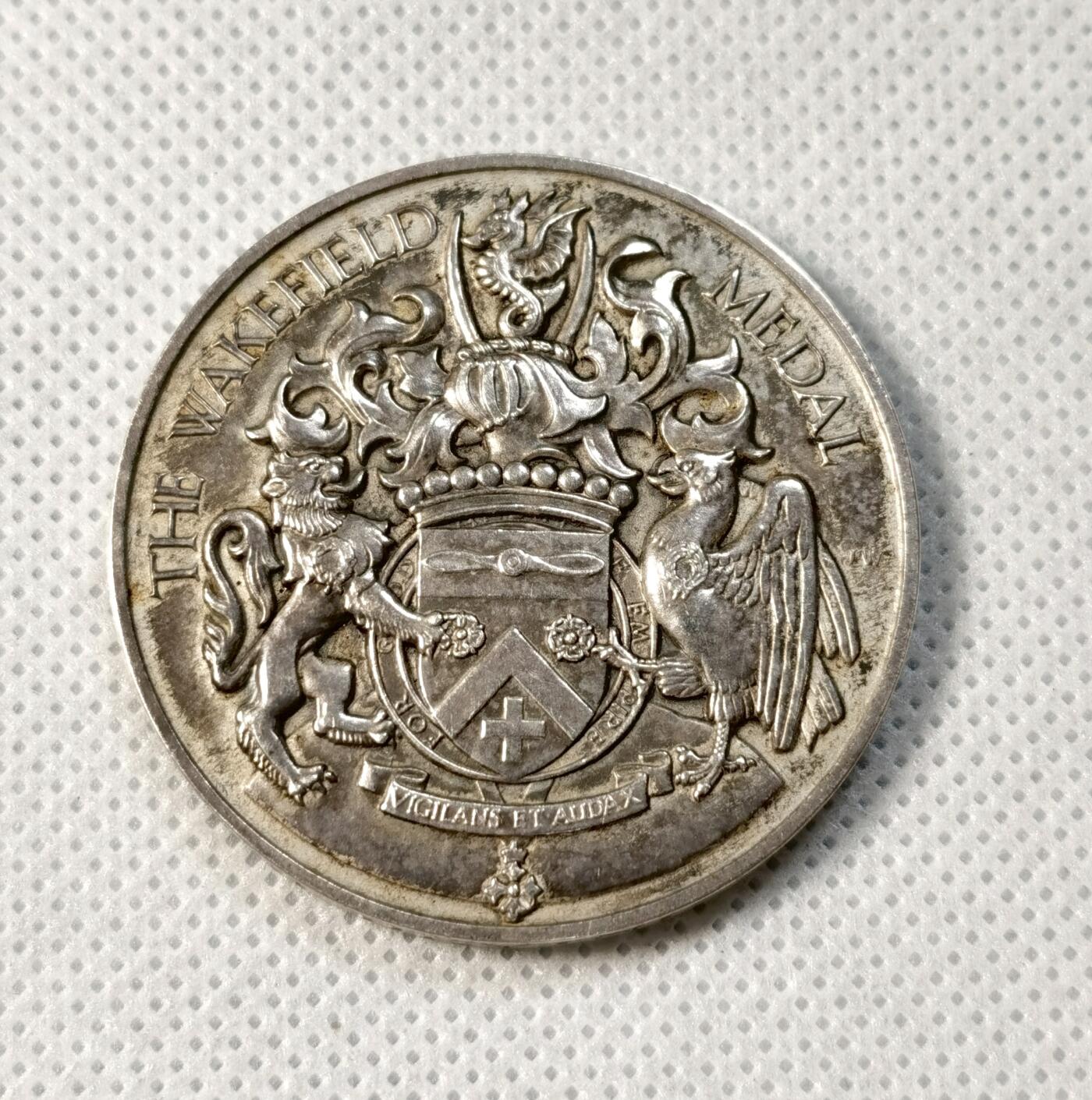 甄臻铺-世界币章拍卖（第35期），送拍享返佣金等优惠多多 The Wakefield Medal 1938年英国殖民地海外比赛纪念银章，正面是狮子和鹰的浮雕图案，中间是盾形徽章，背面刻有NRA BRITISH COLONIES AND PROTECTORATES OVERSEAS MATCH字样。直径41.3毫米，重43.3克，边缘刻有获奖者及日期字样