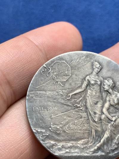 《竞宝斋》第423场 周日，周一，周二  3场连拍 （全场包邮） 法国鲁夫运河工程银质纪念章 22.9克 35.8mm  普通外拍 3200成交 正面：六边形盾徽上刻有年份1775， 图案区域标注1911-1916年及签名“GREGOIRE”；底部铭文“致鲁夫大型海上隧道的合作者与工人们”。背面：正在开凿的隧道中，一名工人倚靠镐头休息；底部铭文“长度7,200米 开口22米/断面300平方米”。 原盒  此章颁发给桥梁与公路总监察长克拉韦耶 