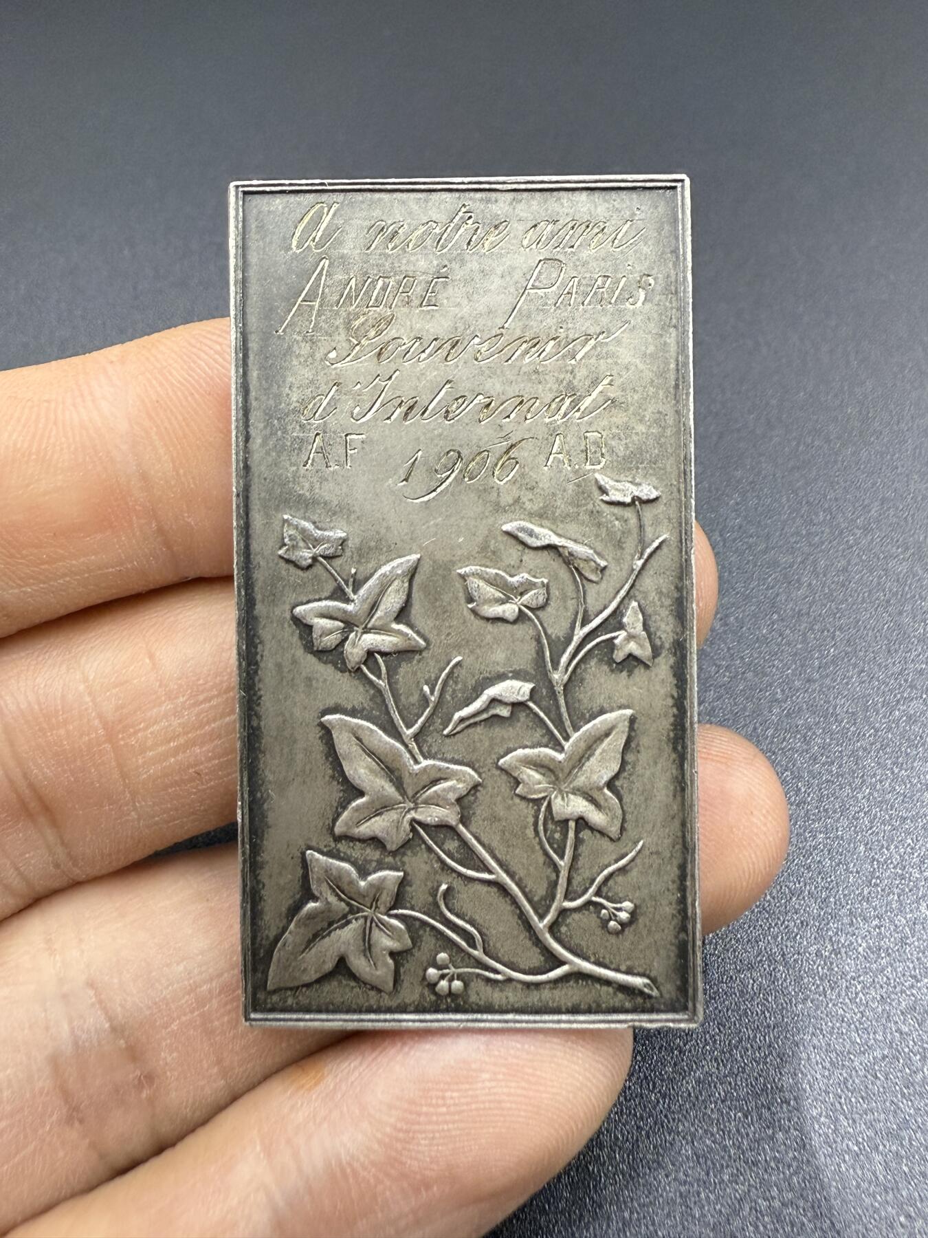 「木头集藏」“双节献礼”——章牌精品专场！ Mouchon～1906年法国艺术银章，尺寸：53.5 x 29 mm，31 g，边铭：丰饶角 ARGENT，背面法语：致我们的朋友安德烈，寄宿学校纪念，1906年，下方刻画常春藤的枝叶与果实，象征友谊、忠诚与永恒，与“纪念”的主题相契合，少见银章，品相不错。