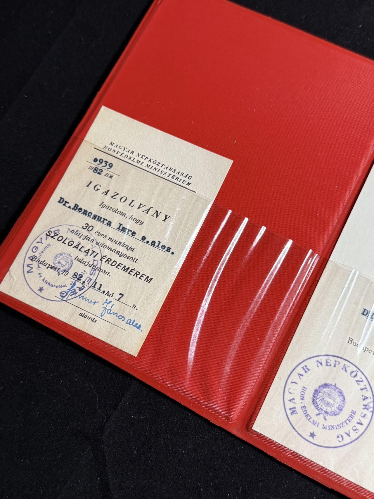 双节同庆！铭记历史！以史为鉴！戎马世界章牌大赏第106期 有新闻报道的军医上校的“服役功勋奖章”证书，授予 Dr. Bencsura Imre 军医中校，Bencsura Imre 不仅是人民军的高级军医，还长期担任 人民军第二军医院外科主任，在外科领域（急性阑尾炎、胆囊疾病、腹部外科）发表多篇学术论文，并在1990年以“军医上校”身份发表临床总结。他在媒体采访中自述“自1952年起从医从军三十年”，并强调军医职业不仅是治病救人，也是心理与社会责任。