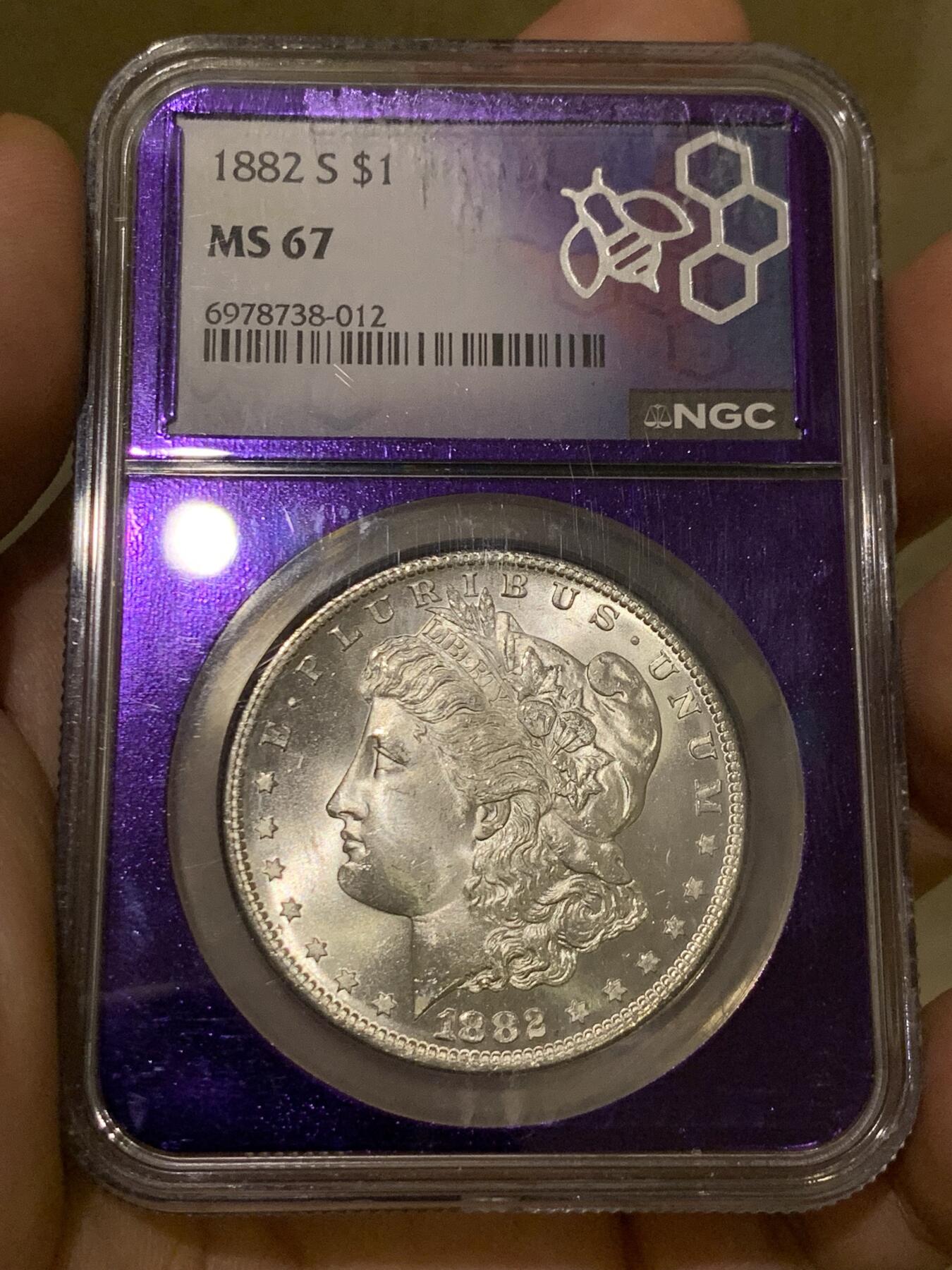 《竞宝斋》第425场 周日，周一  2场连拍 （全场包邮） NGC MS67 美国 1882-S 摩根银币 相当稀有和好看的暗紫色蜜蜂图案评级盒 配上收藏级别的分数 是不可多得的收藏佳品