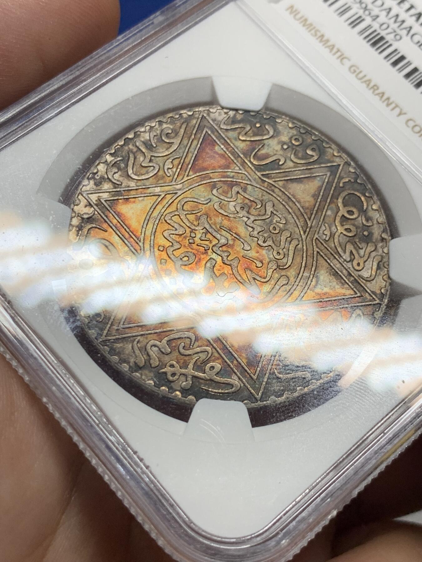 《竞宝斋》第428场 周日，周一  2场连拍 （全场包邮） NGC UNCD 摩洛哥AH1299（1882年）10迪拉姆银币，稀有版别仅次于AH1313，味道币味道足，五彩包浆锋利感十足，状态极佳。疑似错杀。