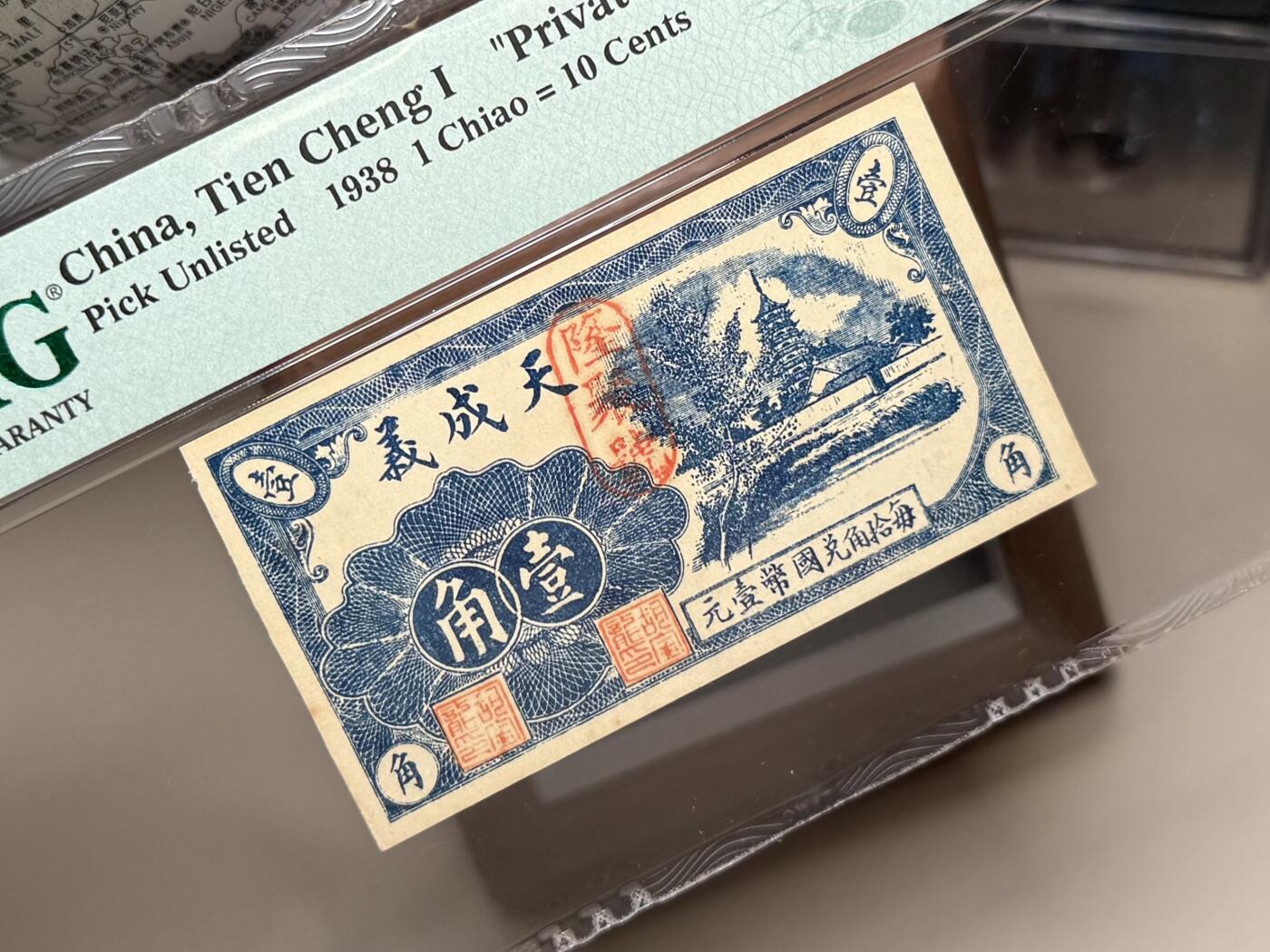 （自动截拍）PMG评级民国纸币专拍第20251106期，全场包邮 【乾奕收藏】出民国27年1938年山东青州天成义隆聚号壹角钱庄票，稀少品种，美国PMG64分，最上角有毛边如图，无背标，介意勿扰
