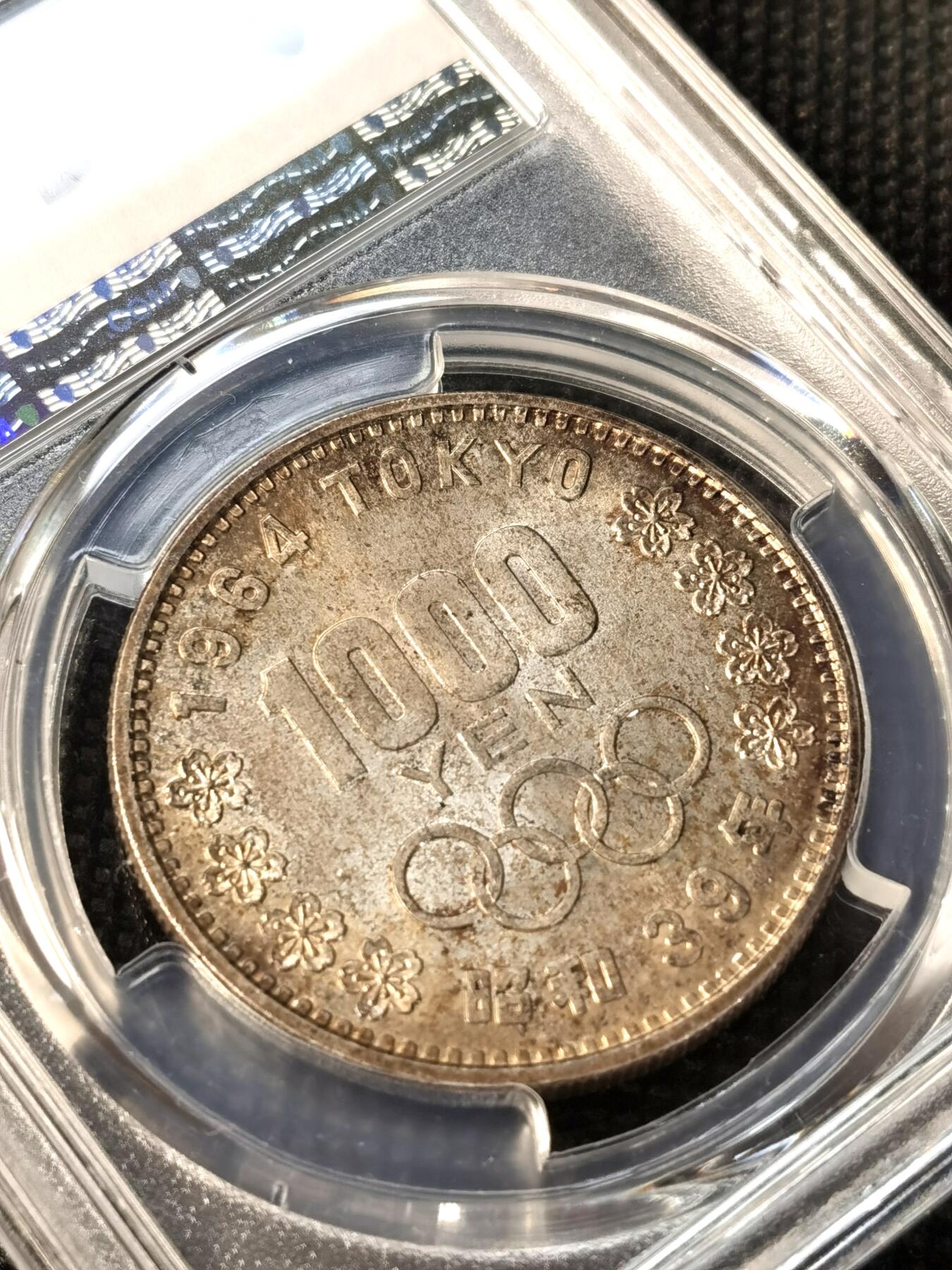 甄臻铺-世界币章拍卖（第36期），送拍享返佣金等优惠多多 PCGS-MS66 日本1964年奥运银币，日本大奥1000日元，标准卷尾币，阴阳彩，正面银光闪闪，背面绚丽的五彩包浆，可遇不可求