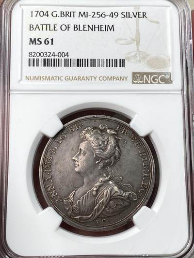 万国钱币拍卖第054期 - NGC MS61 1704年英国布伦海姆战役纪念银章 34毫米，原味好品。正面刻有安妮女王头像，背面描绘布伦海姆战役场景，带有"DE GALL ET BAUD BLENHEIM"字样。 这枚银章是英国历史上的重要纪念章，布伦海姆战役是英国历史上著名的军事胜利之一。
