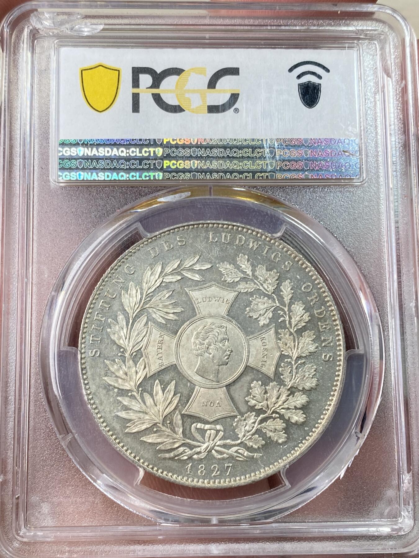 万国钱币拍卖第054期 PCGS MS65 1827巴伐利亚路德维希勋章历史泰勒 1827年8月25日，路德维希一世以国王之名设立了路德维希勋章，用以表彰为王国服务满50周年的杰出人员，并敕令造币厂发行此历史泰勒加以纪念。系列中的罕见品种，BU级别更是难得一见，丝绸地板黄油转光。（评级盒背面左上缺角）