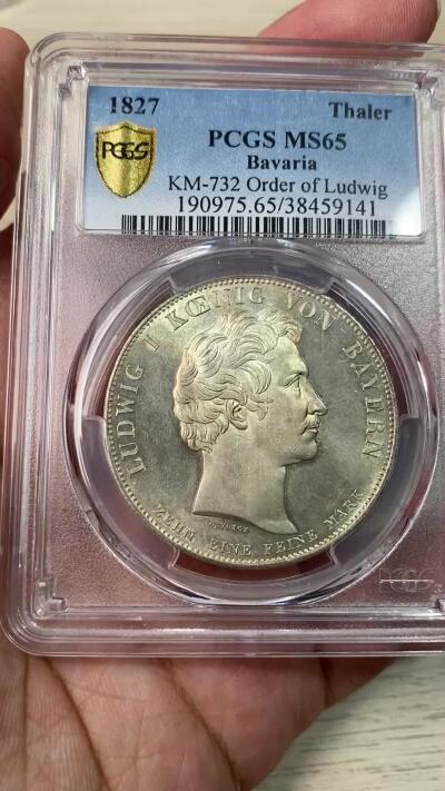 万国钱币拍卖第054期 PCGS MS65 1827巴伐利亚路德维希勋章历史泰勒 1827年8月25日，路德维希一世以国王之名设立了路德维希勋章，用以表彰为王国服务满50周年的杰出人员，并敕令造币厂发行此历史泰勒加以纪念。系列中的罕见品种，BU级别更是难得一见，丝绸地板黄油转光。（评级盒背面左上缺角）