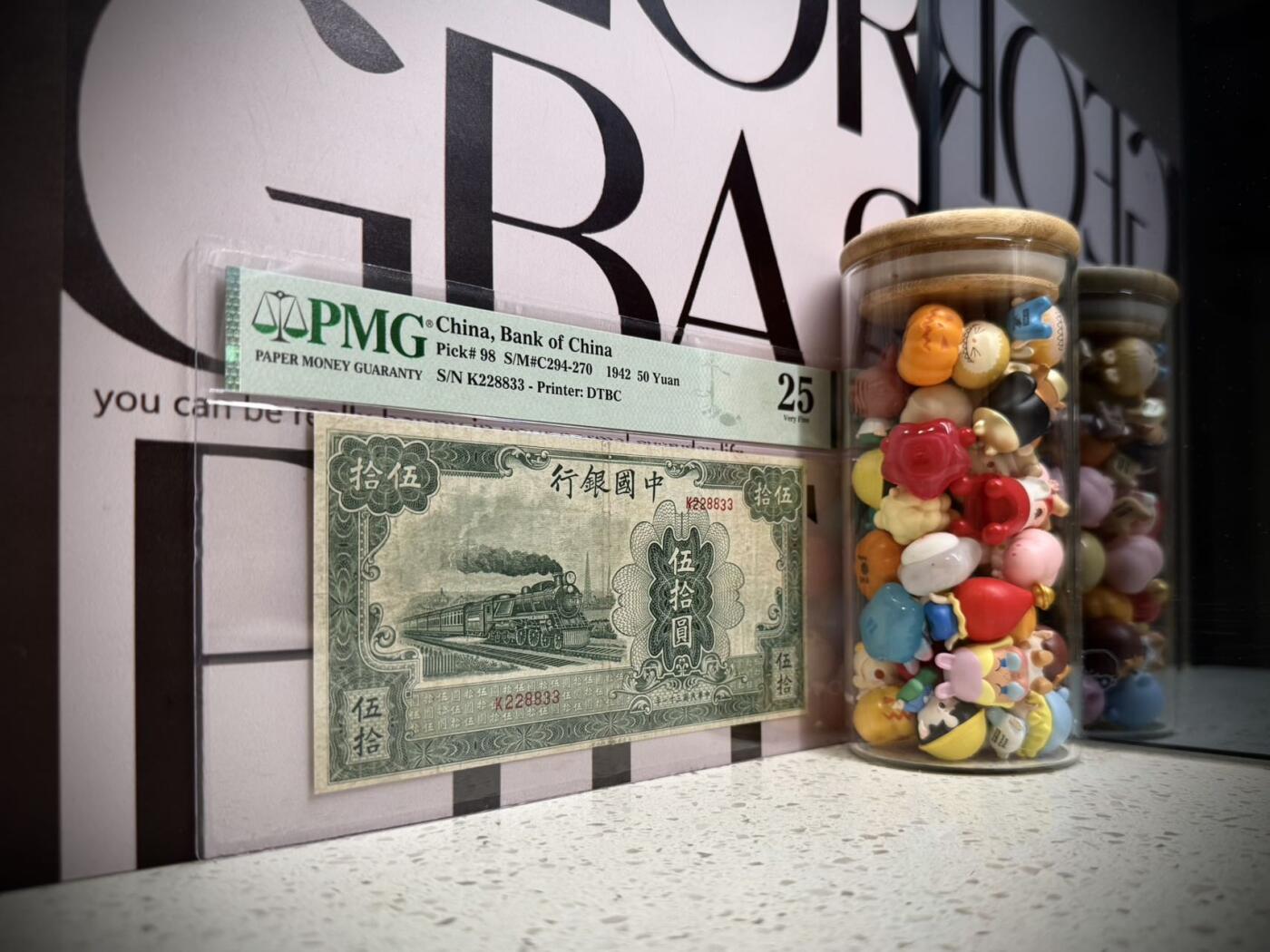 （自动截拍）PMG评级民国纸币专拍第20251115期，全场包邮 【乾奕收藏】出民国31年1942年中国银行大东版伍拾圆，大东三剑客之一，交行，中国银行，中国农民银行共用相同图案印刷，仅行名、签名和颜色不同，绿色火车图案。228833，三对子超级靓号，号码全程无47，美国PMG25分