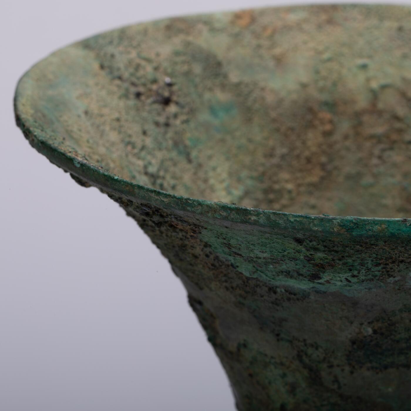 日本大阪雅和auction 2025金秋競賣會第一期 商 饕餮紋花觚 尺寸:W:14.5 H:25.5cm 備註:商代饕餮紋花觚，通體造型高峻挺拔，線條勻稱流暢，腹部微鼓，頸部修長，口沿外撇，圈足穩健。全器以精緻的饕餮紋為主紋，繁而不亂，層次分明，展現出商代青銅藝術的莊嚴與神祕。花紋間飾以雷紋、夔龍及細密的幾何紋飾，刀痕遒勁，鑄工嚴謹。整器包漿古潤，青銅色澤沉靜雅緻，氣韻雄渾，威嚴中蘊含典雅之美。此觚不僅為祭祀禮器之代表，亦體現了商人敬天重禮的信仰與