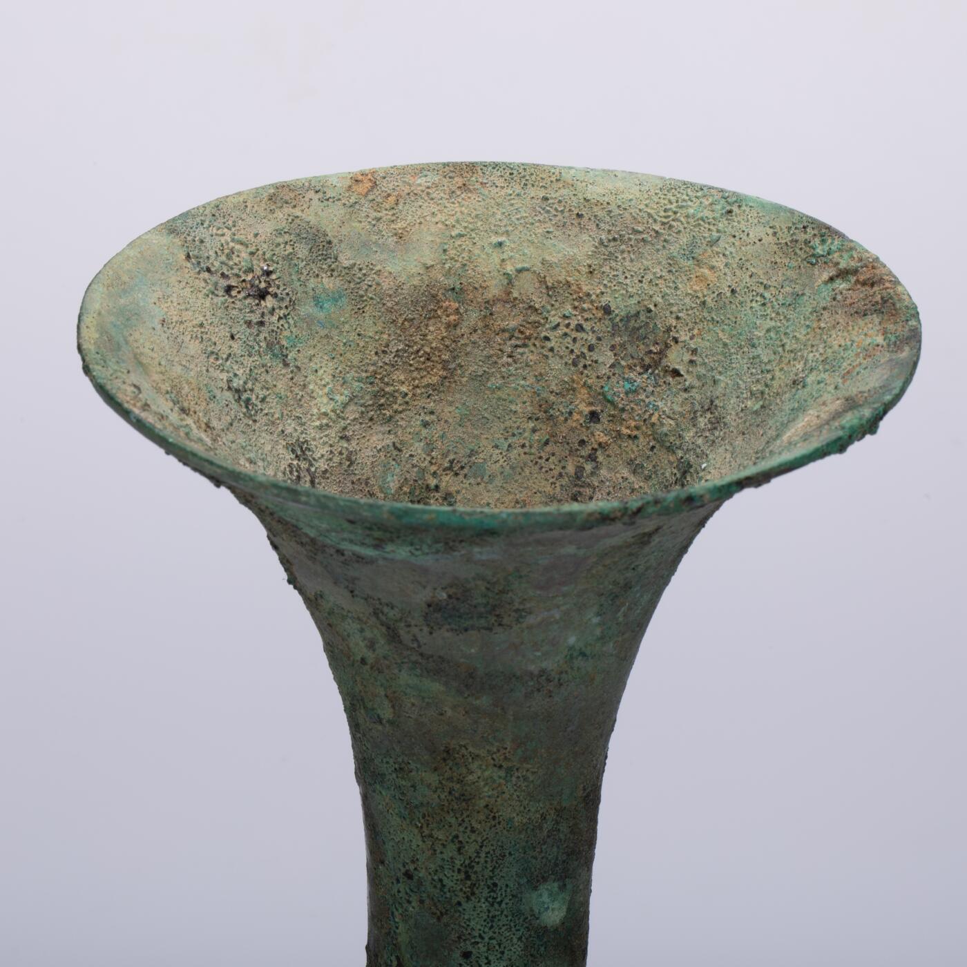 日本大阪雅和auction 2025金秋競賣會第一期 商 饕餮紋花觚 尺寸:W:14.5 H:25.5cm 備註:商代饕餮紋花觚，通體造型高峻挺拔，線條勻稱流暢，腹部微鼓，頸部修長，口沿外撇，圈足穩健。全器以精緻的饕餮紋為主紋，繁而不亂，層次分明，展現出商代青銅藝術的莊嚴與神祕。花紋間飾以雷紋、夔龍及細密的幾何紋飾，刀痕遒勁，鑄工嚴謹。整器包漿古潤，青銅色澤沉靜雅緻，氣韻雄渾，威嚴中蘊含典雅之美。此觚不僅為祭祀禮器之代表，亦體現了商人敬天重禮的信仰與