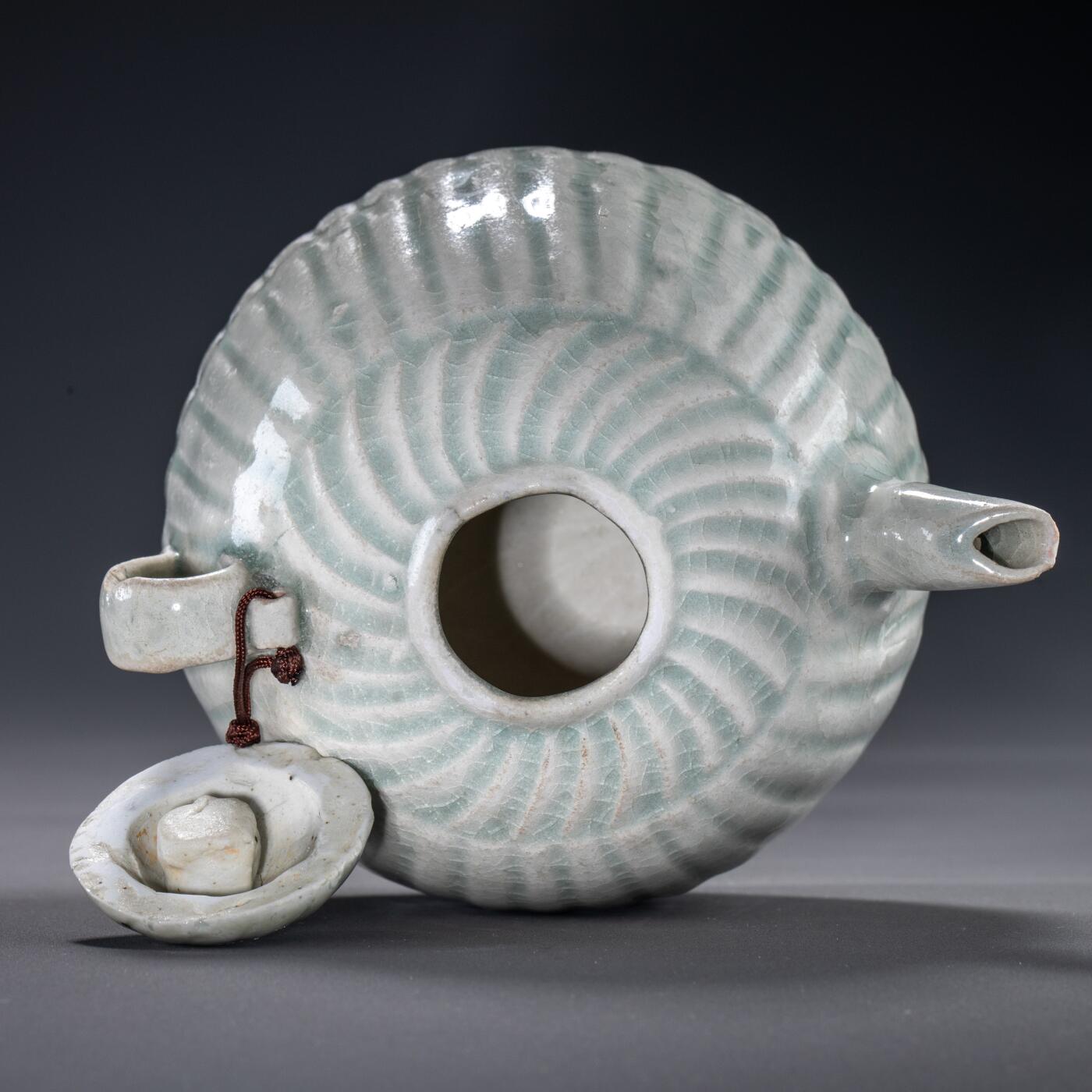 日本大阪雅和auction 2025金秋競賣會第一期 宋 湖田窯執壺 尺寸:W:11 H:9cm 備註:盒付   本器為宋代湖田窯所製執壺，通體施青白釉，釉色清潤柔和，溫潤如玉。壺身與蓋飾以螺旋剔刻紋，刀工流暢，層次分明，體現極高工藝水準。壺形端正，流口、把手與蓋鈕比例協調，實用與美觀兼具。此壺保存完好，為古瓷愛好者與茶道收藏者不可多得之佳品。