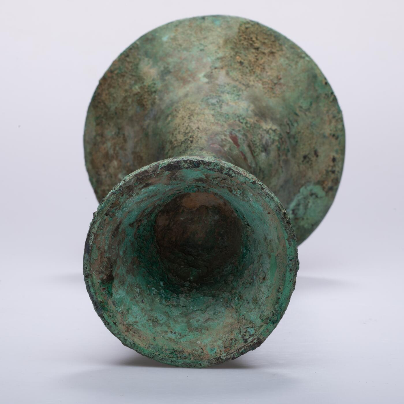 日本大阪雅和auction 2025金秋競賣會第一期 商 饕餮紋花觚 尺寸:W:14.5 H:25.5cm 備註:商代饕餮紋花觚，通體造型高峻挺拔，線條勻稱流暢，腹部微鼓，頸部修長，口沿外撇，圈足穩健。全器以精緻的饕餮紋為主紋，繁而不亂，層次分明，展現出商代青銅藝術的莊嚴與神祕。花紋間飾以雷紋、夔龍及細密的幾何紋飾，刀痕遒勁，鑄工嚴謹。整器包漿古潤，青銅色澤沉靜雅緻，氣韻雄渾，威嚴中蘊含典雅之美。此觚不僅為祭祀禮器之代表，亦體現了商人敬天重禮的信仰與