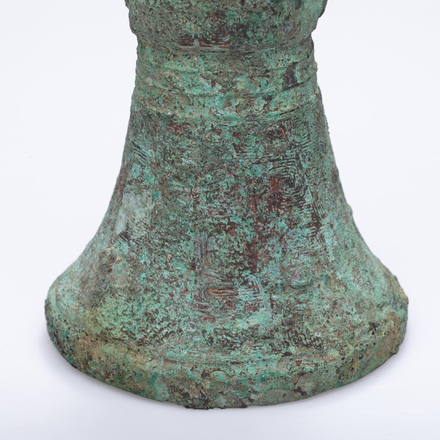 日本大阪雅和auction 2025金秋競賣會第一期 商 饕餮紋花觚 尺寸:W:14.5 H:25.5cm 備註:商代饕餮紋花觚，通體造型高峻挺拔，線條勻稱流暢，腹部微鼓，頸部修長，口沿外撇，圈足穩健。全器以精緻的饕餮紋為主紋，繁而不亂，層次分明，展現出商代青銅藝術的莊嚴與神祕。花紋間飾以雷紋、夔龍及細密的幾何紋飾，刀痕遒勁，鑄工嚴謹。整器包漿古潤，青銅色澤沉靜雅緻，氣韻雄渾，威嚴中蘊含典雅之美。此觚不僅為祭祀禮器之代表，亦體現了商人敬天重禮的信仰與