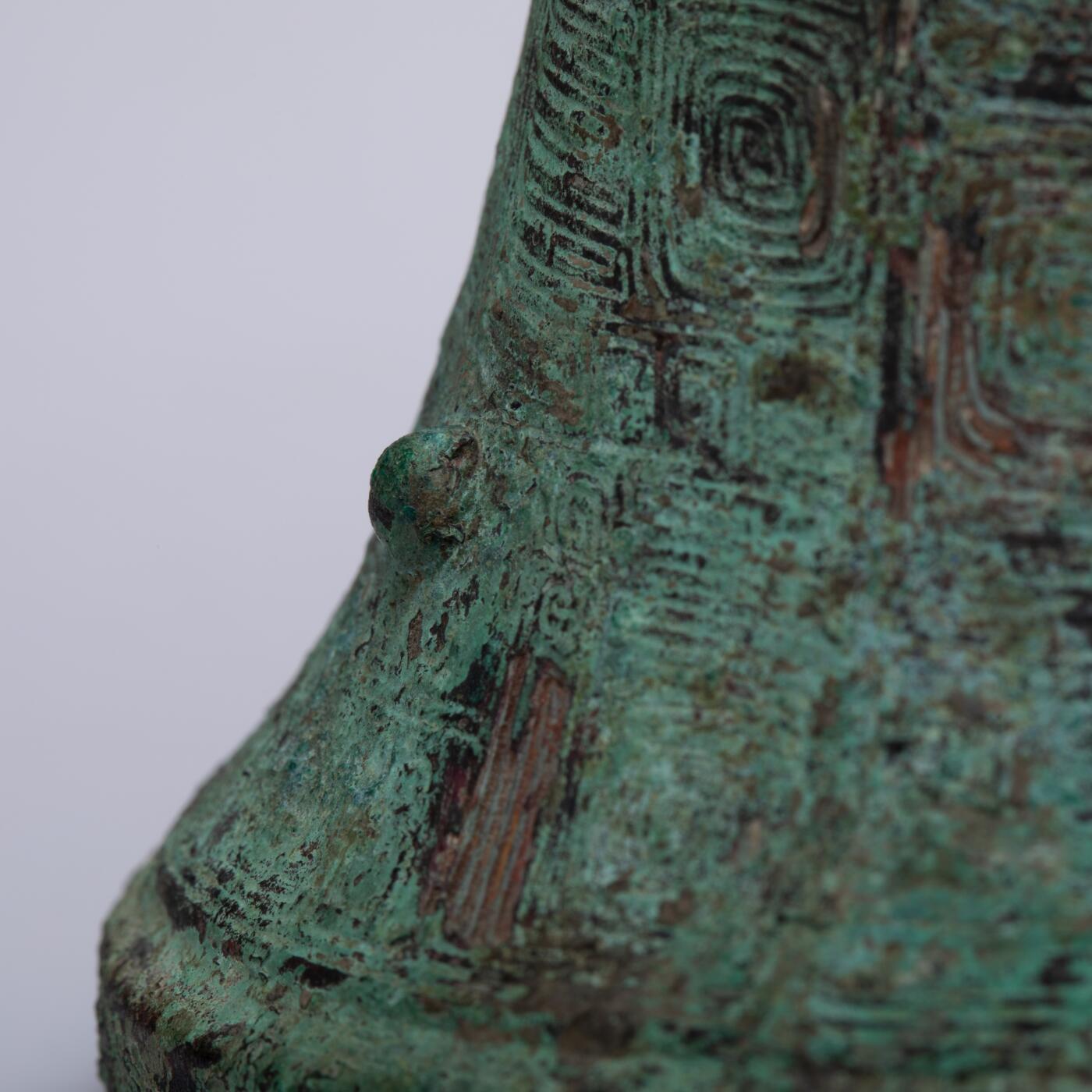 日本大阪雅和auction 2025金秋競賣會第一期 商 饕餮紋花觚 尺寸:W:14.5 H:25.5cm 備註:商代饕餮紋花觚，通體造型高峻挺拔，線條勻稱流暢，腹部微鼓，頸部修長，口沿外撇，圈足穩健。全器以精緻的饕餮紋為主紋，繁而不亂，層次分明，展現出商代青銅藝術的莊嚴與神祕。花紋間飾以雷紋、夔龍及細密的幾何紋飾，刀痕遒勁，鑄工嚴謹。整器包漿古潤，青銅色澤沉靜雅緻，氣韻雄渾，威嚴中蘊含典雅之美。此觚不僅為祭祀禮器之代表，亦體現了商人敬天重禮的信仰與