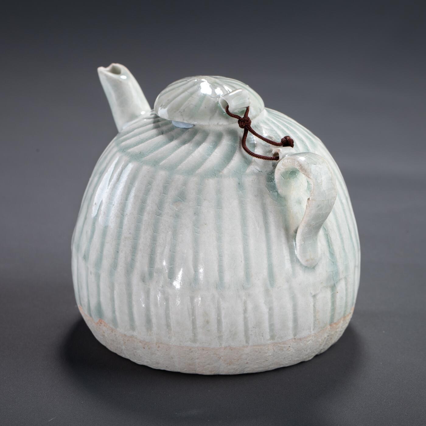 日本大阪雅和auction 2025金秋競賣會第一期 宋 湖田窯執壺 尺寸:W:11 H:9cm 備註:盒付   本器為宋代湖田窯所製執壺，通體施青白釉，釉色清潤柔和，溫潤如玉。壺身與蓋飾以螺旋剔刻紋，刀工流暢，層次分明，體現極高工藝水準。壺形端正，流口、把手與蓋鈕比例協調，實用與美觀兼具。此壺保存完好，為古瓷愛好者與茶道收藏者不可多得之佳品。