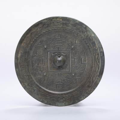 日本大阪雅和auction 2025金秋競賣會第一期 - 漢 走獸紋規矩鏡 尺寸:D:14cm 備註:盒付   此面漢代走獸紋規矩鏡，鏡體渾圓厚重，通體黑漆古包漿，色澤沉潤柔和，鏡背以精細線條鑄出走獸紋飾，或奔或躍，神態生動，間以幾何規矩紋相間佈局，構圖嚴謹而富節奏感。鏡紐高起，形制端正，邊廓勻整，展現漢代青銅鏡工藝的成熟與規範之美。此類鏡多寓意驅邪護身、吉祥長安，包漿溫潤，光澤深邃，鏡面保存完好，實屬難得。其兼具實用與審美價值，彰顯漢代金屬藝術的莊重典