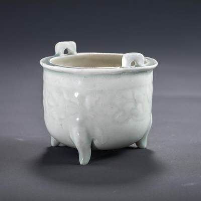 日本大阪雅和auction 2025金秋競賣會第一期 - 宋 湖田窯印花香爐 尺寸:D:7.5 H:7cm 備註:盒付   此件香爐出自宋代湖田窯，器形端莊，小巧雅緻，爐身三足承托，雙耳對稱，線條柔和流暢。通體施青白釉，釉色潤澤如玉，隱現淺浮雕印花紋飾，含蓄典雅，展現宋代審美情趣。湖田窯為宋代重要民窯之一，擅長青白釉器物，深受士大夫階層喜愛。本器保存良好，無磕無裂，為香道愛好者與古陶瓷藏家難得之佳品。