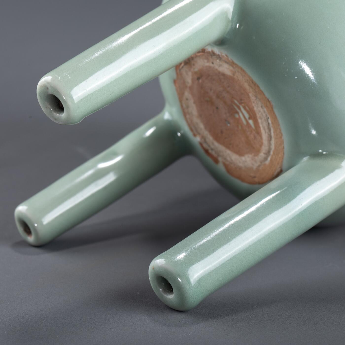 日本大阪雅和auction 2025金秋競賣會第一期 南宋 龍泉窯葱管三足鼎 尺寸:W:13 H:20cm 備註:盒付   此件南宋龍泉窯青釉鼎式爐，通體施粉青釉，色澤清潤如玉，呈柔和青翠之調，光潔內斂，頗具玉質之美。爐身圓腹，雙耳高聳上揚，三足中空、形似蔥管，挺拔穩健。整體比例勻稱，線條簡潔流暢，盡顯宋代器物的典雅之風。此式承襲青銅禮鼎造型，融祭器莊嚴與文房雅玩於一體，既可焚香，又具觀賞之趣，充分體現宋人「以瓷擬玉」之審美理想與高潔意趣。