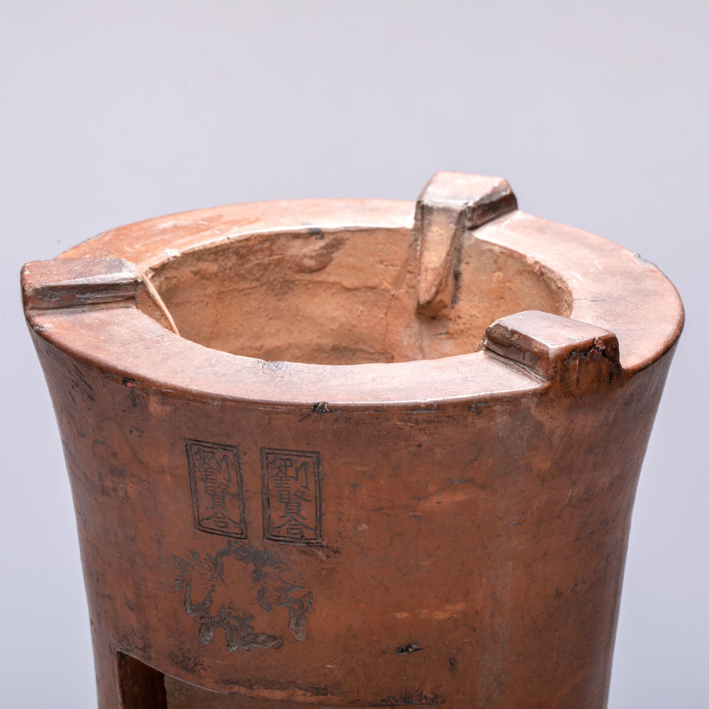 日本大阪雅和auction 2025金秋競賣會第一期 清 劉賢合款涼爐 尺寸:W:16 H:25cm 備註:此件紅泥涼爐，通體呈溫潤赤褐色，質地堅實細膩。爐身上部微敞，線條挺拔簡練，正面鏤空幾何紋飾，造型古樸而富有裝飾性。爐面刻「劉賢合」款，字體工整，彰顯製作者之巧思與自信。整體造型端莊穩重，器壁厚實，既具實用功能，又有極高的藝術觀賞價值，乃集工藝與美感於一體之紅泥佳作。