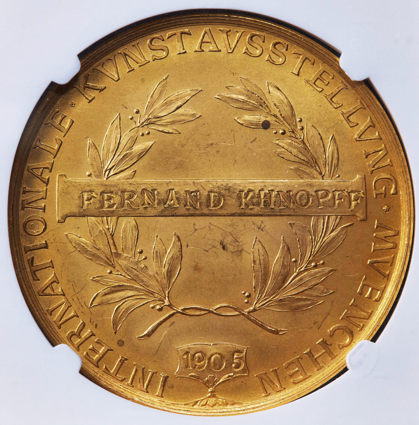 【俄甄集藏】2025年(044)11-12星期三晚 19:30 全场包邮 德国巴伐利亚1905年雅典娜坐像慕尼黑艺术合作社金质奖章，NGC MS64，雕刻家A·博尔舍作品，正面希腊神话智慧女神雅典娜戎装像，伸手触碰象征“艺术与和平”的橄榄树，背面橄榄枝环绕的铭牌上刻有获奖者姓名“费南德·赫诺夫”，外圈文字为慕尼黑国际艺术展，重37.97克，稀有品种