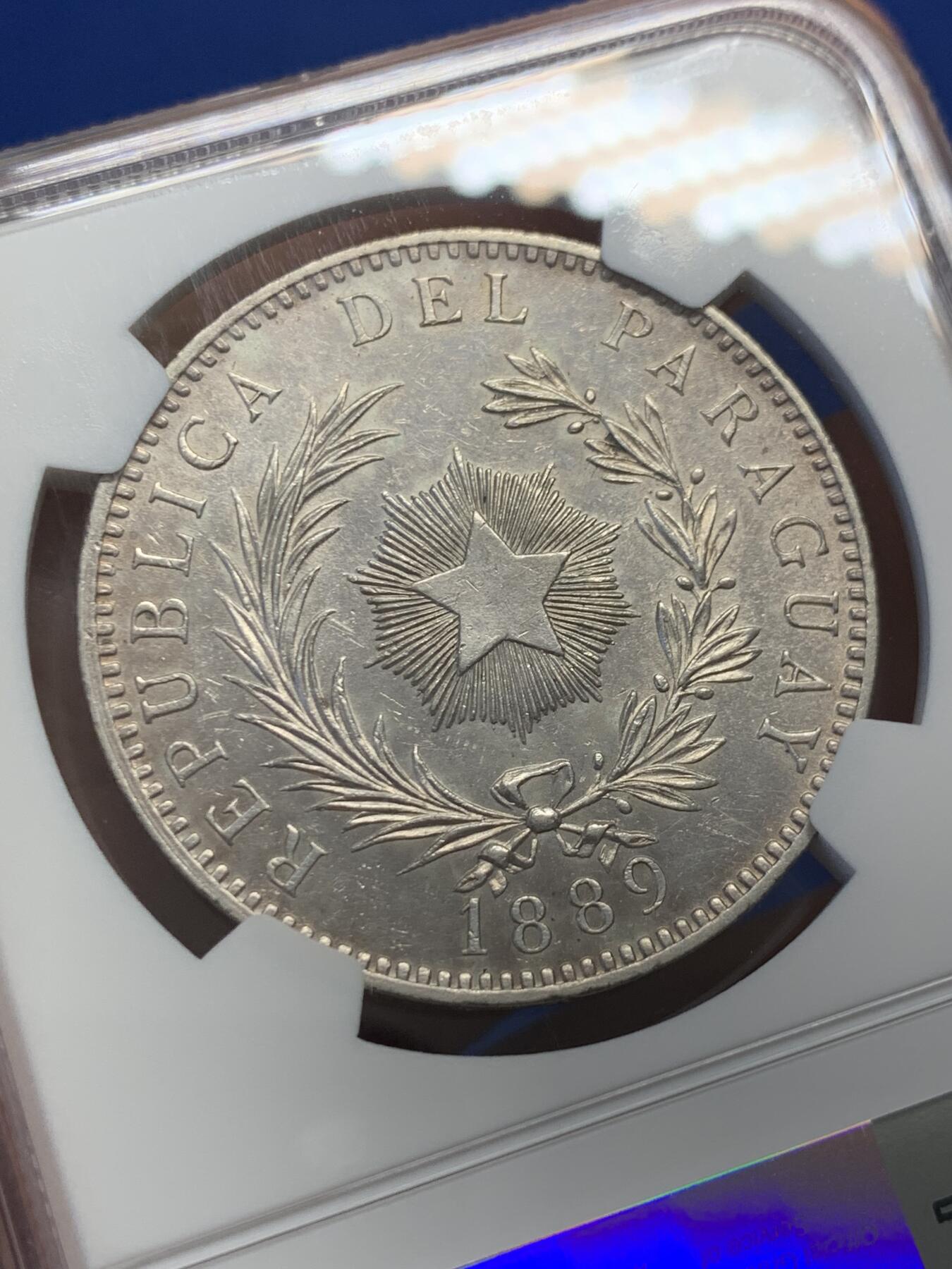 《竞宝斋》第436场 周日，周一2场连拍 （全场包邮） NGC UNCD 巴拉圭1889年雄狮1比索大银币，正面图为一头卷毛雄狮蹲坐守卫着自由之竿和自由之帽，反面图中间有一枚光芒四射的五角星，以此纪念1811年5月摆脱西班牙殖民统治获得独立。