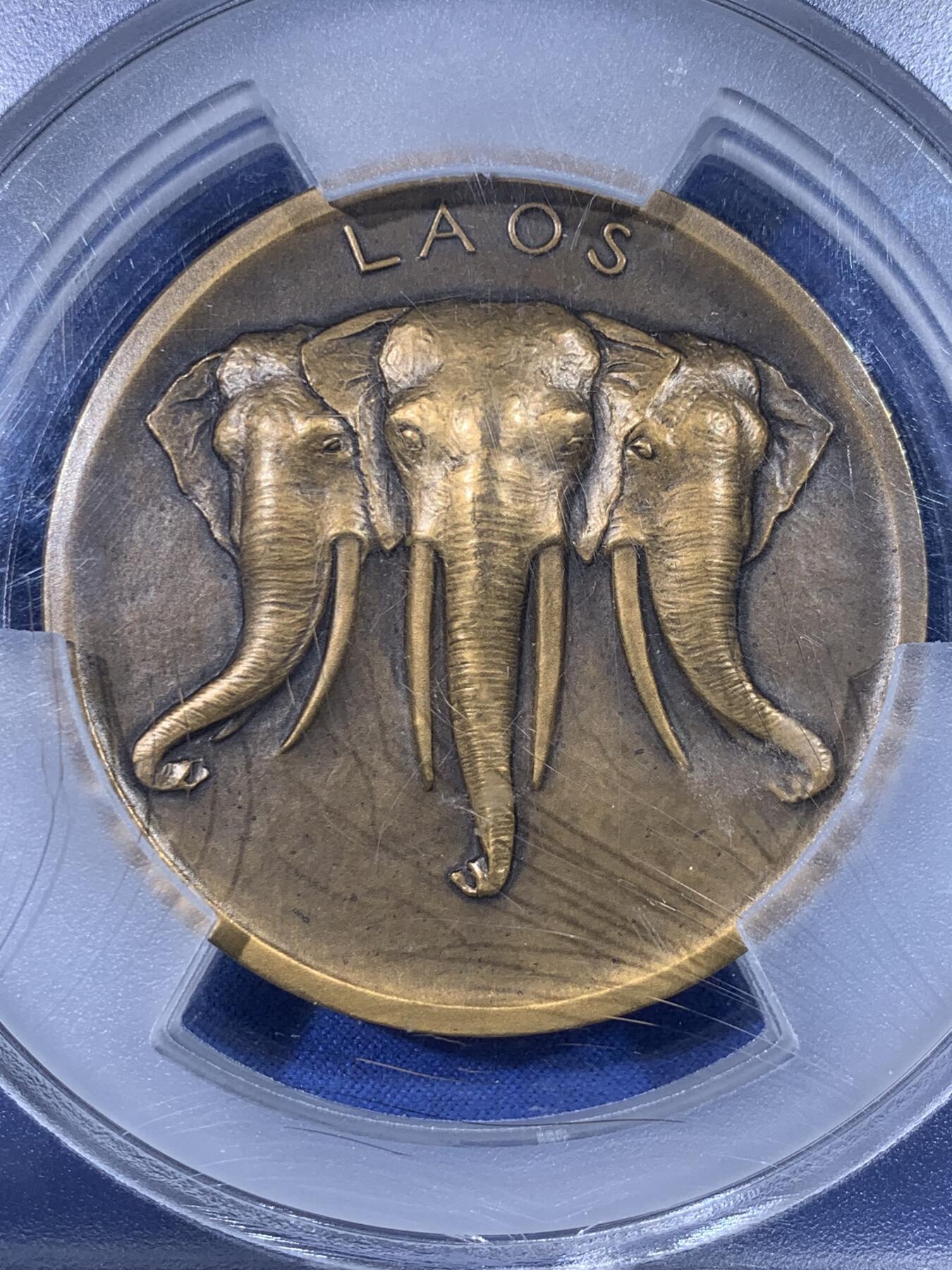 《竞宝斋》第436场 周日，周一2场连拍 （全场包邮） PCGS SP64 唯一冠军分 法属印度支那1931年老挝大铜章 59毫米 97.16克大规格 巴黎殖民博览会纪念 正面身着传统服饰青年男女吹奏乐器 背面三头象为老挝古代国徽 盒子有轻微裂纹 细节见图 加大加厚盒装