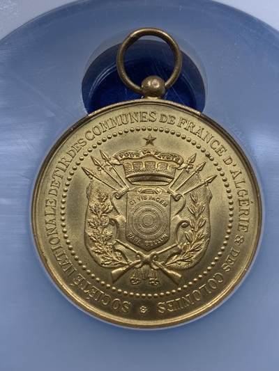 《竞宝斋》第437场 周日，周一2场连拍 （全场包邮） NGC MS64 约1890年代 法属阿尔及利亚殖民地射击节镀金大铜章，殖民地射击节非常稀少，个人首见，金水很足。经典的玛丽安娜女神+女性天使，华丽优美。加大加厚盒封装，收藏级高分