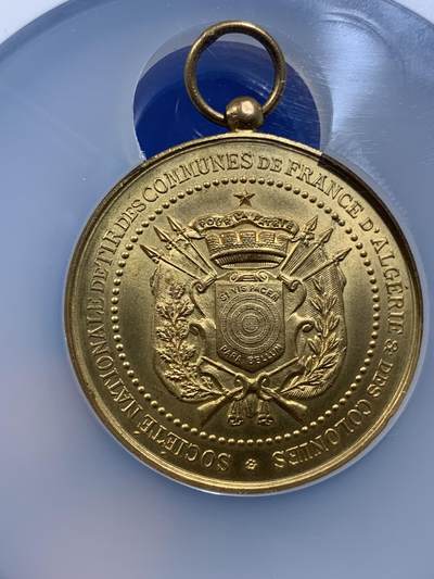 《竞宝斋》第437场 周日，周一2场连拍 （全场包邮） NGC MS64 约1890年代 法属阿尔及利亚殖民地射击节镀金大铜章，殖民地射击节非常稀少，个人首见，金水很足。经典的玛丽安娜女神+女性天使，华丽优美。加大加厚盒封装，收藏级高分