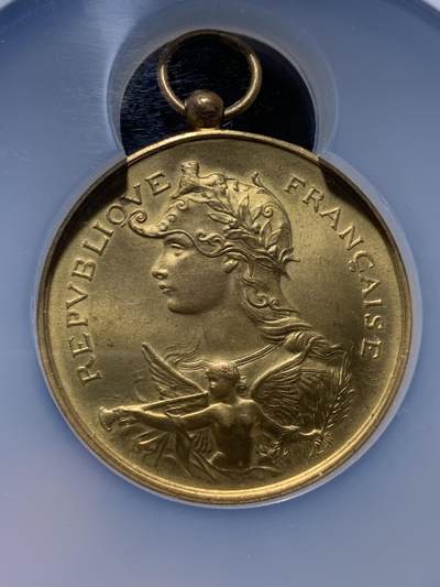 《竞宝斋》第437场 周日，周一2场连拍 （全场包邮） NGC MS64 约1890年代 法属阿尔及利亚殖民地射击节镀金大铜章，殖民地射击节非常稀少，个人首见，金水很足。经典的玛丽安娜女神+女性天使，华丽优美。加大加厚盒封装，收藏级高分