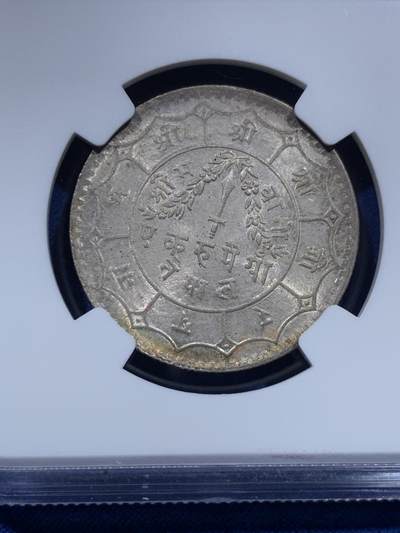 《竞宝斋》第437场 周日，周一2场连拍 （全场包邮） NGC MS64 尼泊尔1934年 1卢比银币。从美国老藏家币夹中拆出，有着长久存放产生的烟灰质感包浆，其6点钟方向有着一抹亮眼的金色月牙包浆，给整币画上点睛之笔，让平凡的品种有了非凡的观感。