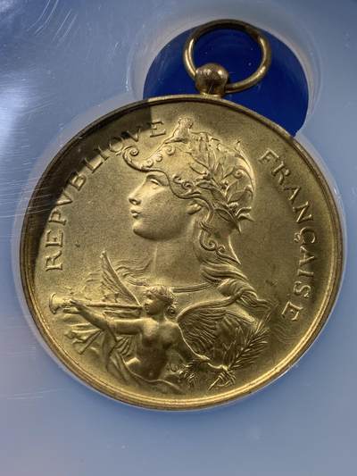 《竞宝斋》第437场 周日，周一2场连拍 （全场包邮） NGC MS64 约1890年代 法属阿尔及利亚殖民地射击节镀金大铜章，殖民地射击节非常稀少，个人首见，金水很足。经典的玛丽安娜女神+女性天使，华丽优美。加大加厚盒封装，收藏级高分