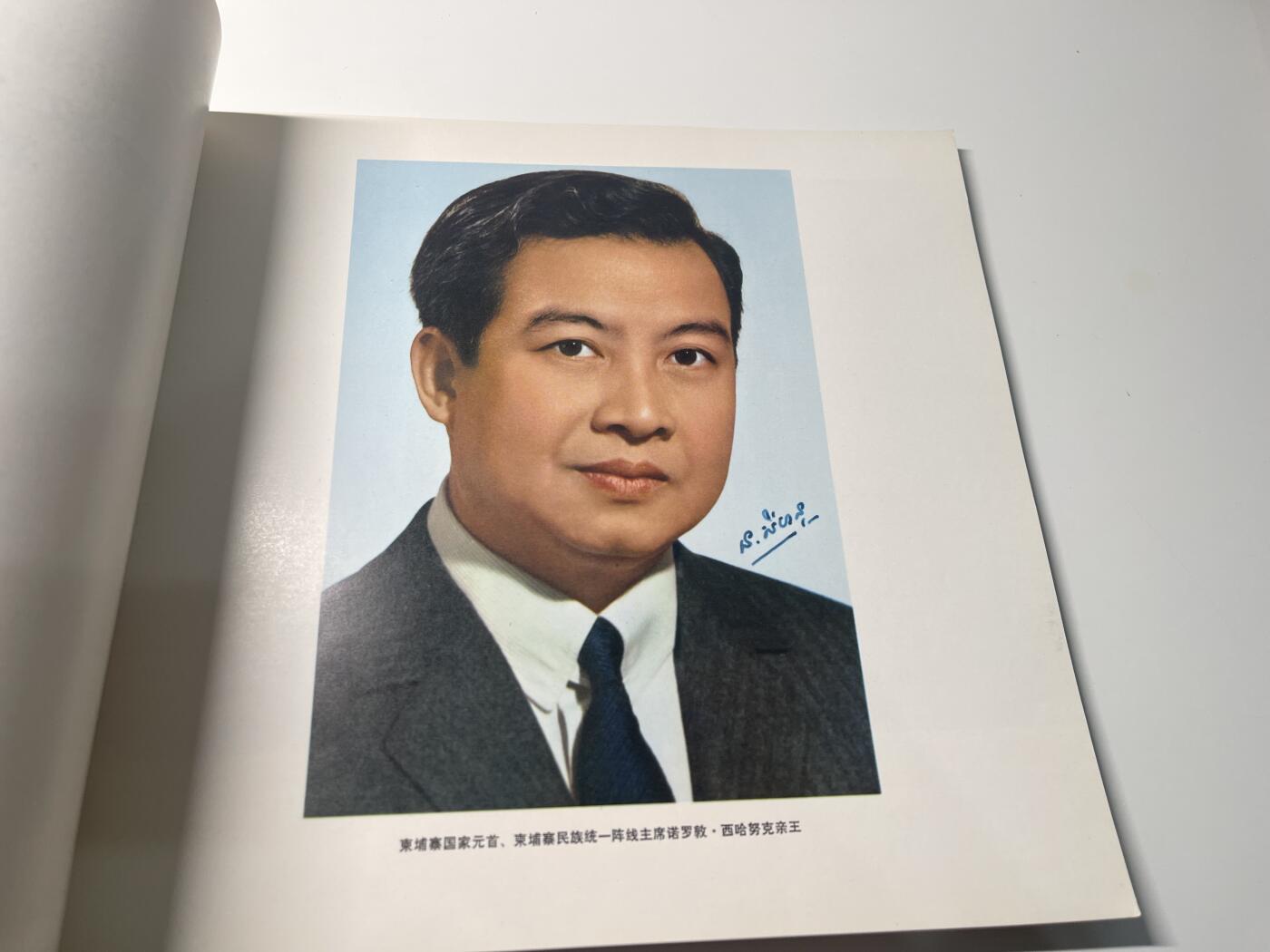 新时代收藏徽章红藏拍卖(第二十八场)  徽章纸品证书杂项 柬埔寨西哈努克亲王在解放区画册 1973年 官方外事画册 一般赠与参与接待人员 和档案馆存档 里面的女学生和演员在波尔布特浩劫中结局应该不太好 这本画册里似乎也有波尔布特的照片 感兴趣可购入自行查找 东西肯定是好东西