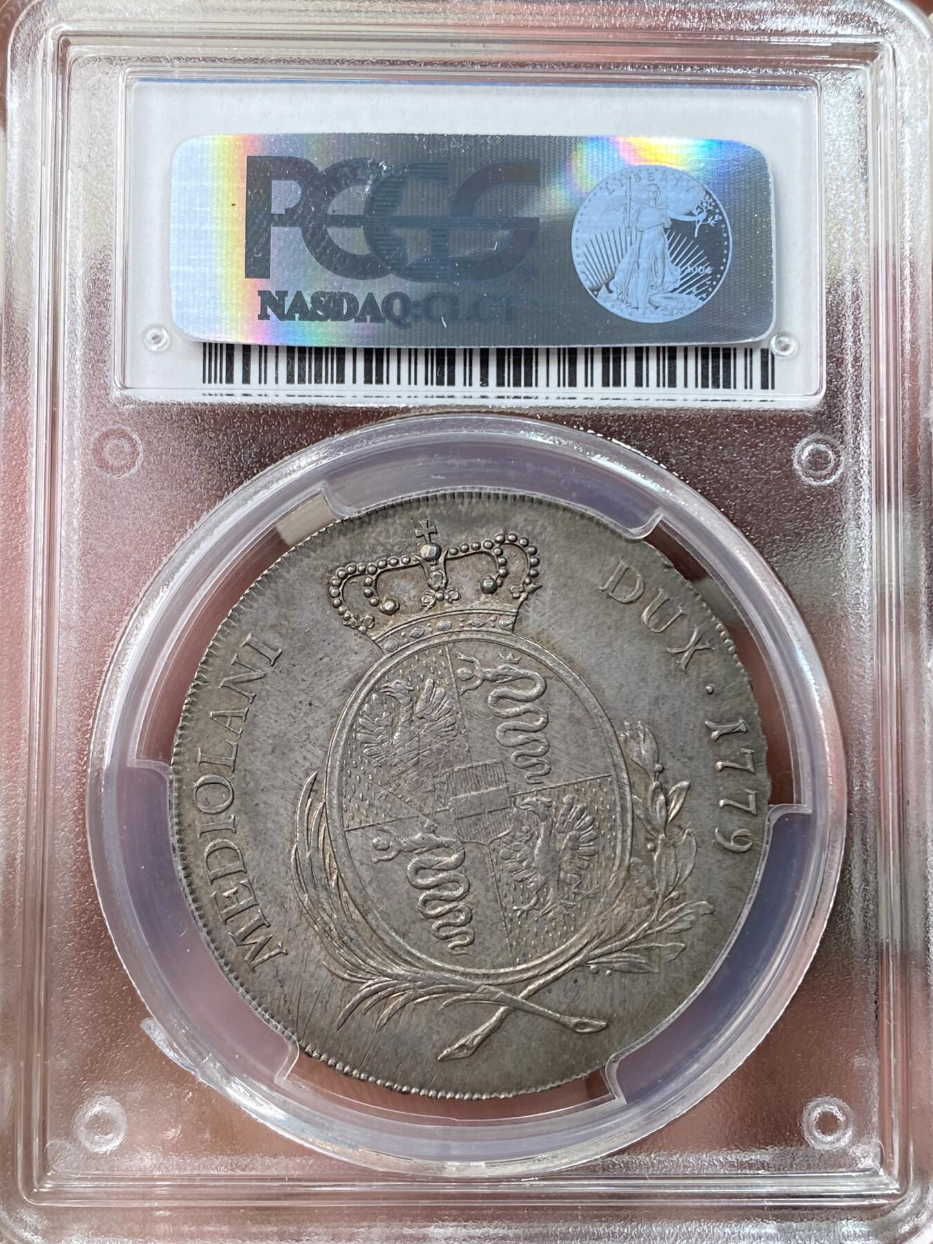 万国钱币拍卖第055期 PCGS MS63 1779意大利米兰公国玛丽亚·特蕾莎女皇Scudo（6里拉）大银 神圣罗马帝国时期哈布斯堡家族统治下的产物 特蕾莎女皇是查理六世的女儿，也是后来两位神罗皇帝约瑟夫二世和利奥波德二世的母亲，背面为米兰公国经典的鹰蛇纹章，此品种常见多为vf品相，均匀欧陆五彩转光，PC唯一冠军分&封面广告币，一共只有四枚评级记录，亚军AU53，季军VF35，断崖式领先的顶级收藏品质。