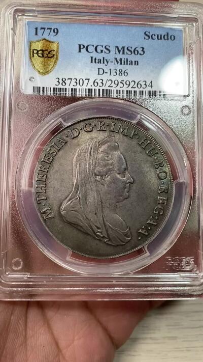 万国钱币拍卖第055期 PCGS MS63 1779意大利米兰公国玛丽亚·特蕾莎女皇Scudo（6里拉）大银 神圣罗马帝国时期哈布斯堡家族统治下的产物 特蕾莎女皇是查理六世的女儿，也是后来两位神罗皇帝约瑟夫二世和利奥波德二世的母亲，背面为米兰公国经典的鹰蛇纹章，此品种常见多为vf品相，均匀欧陆五彩转光，PC唯一冠军分&封面广告币，一共只有四枚评级记录，亚军AU53，季军VF35，断崖式领先的顶级收藏品质。